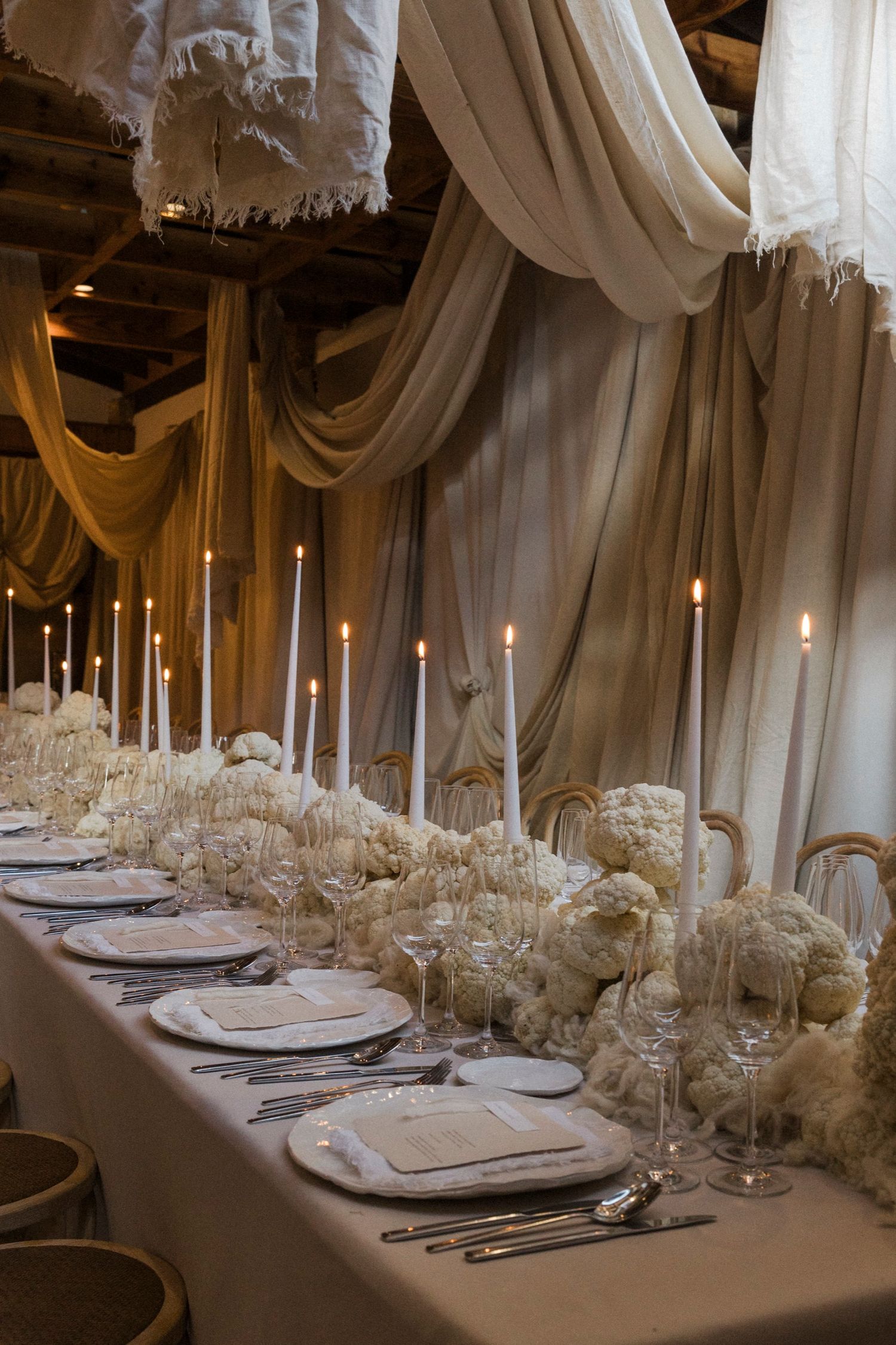 Romantic table setting with white floral runner, taper candles, and luxurious place settings.