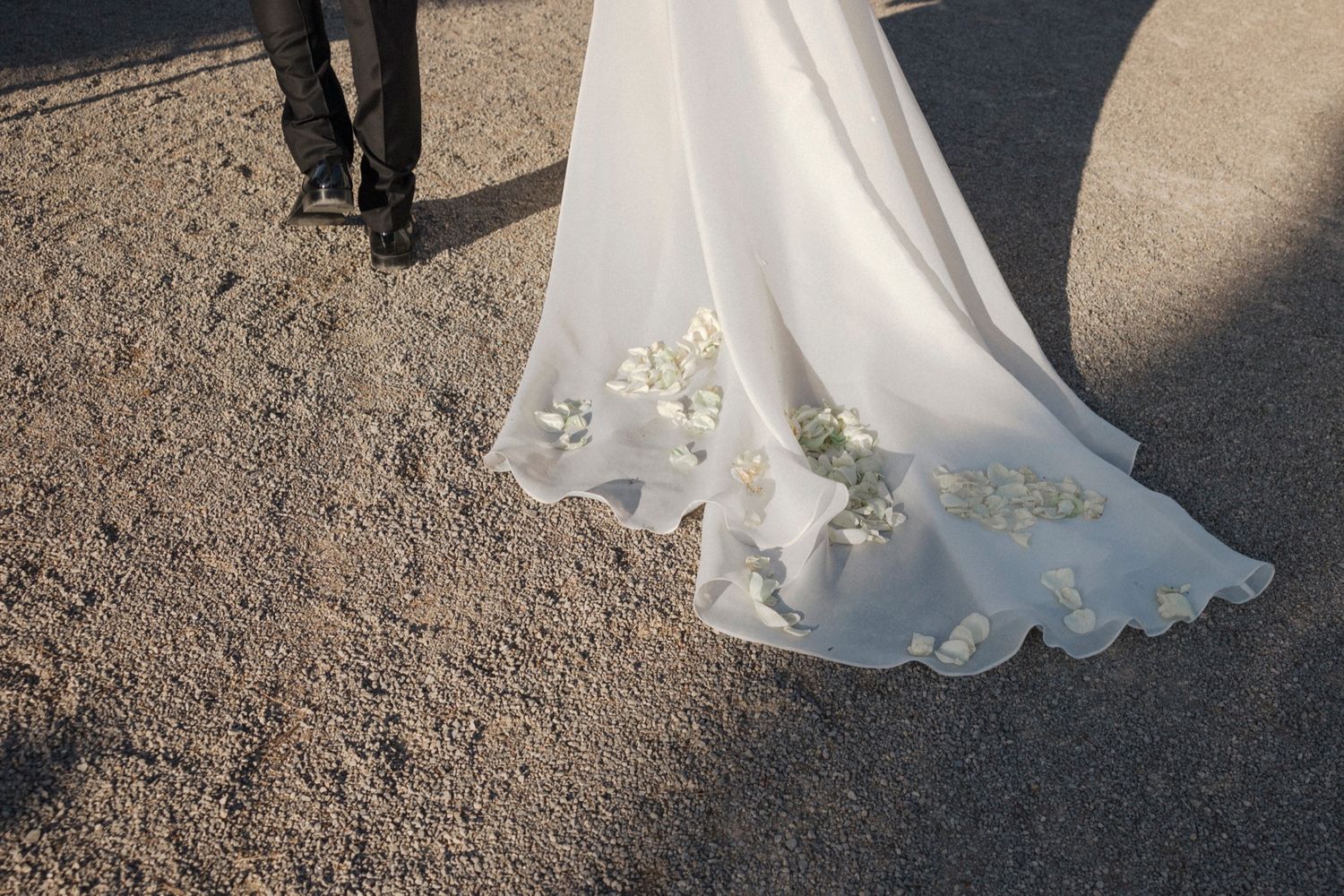 Wedding dress details shown against stone pathway at outdoor venue.