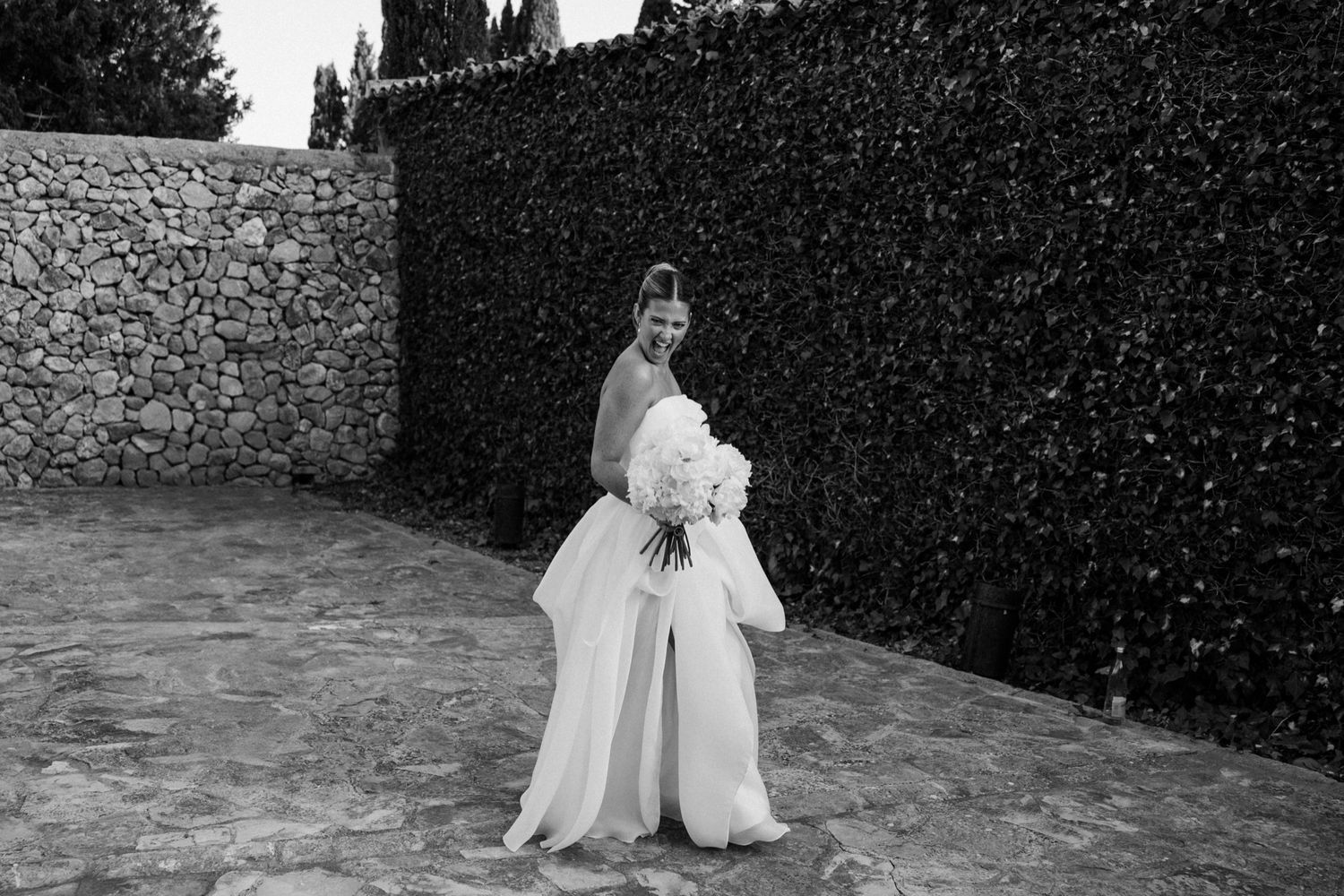 Elegant stone courtyard setting with cypress trees provides backdrop for wedding photos.