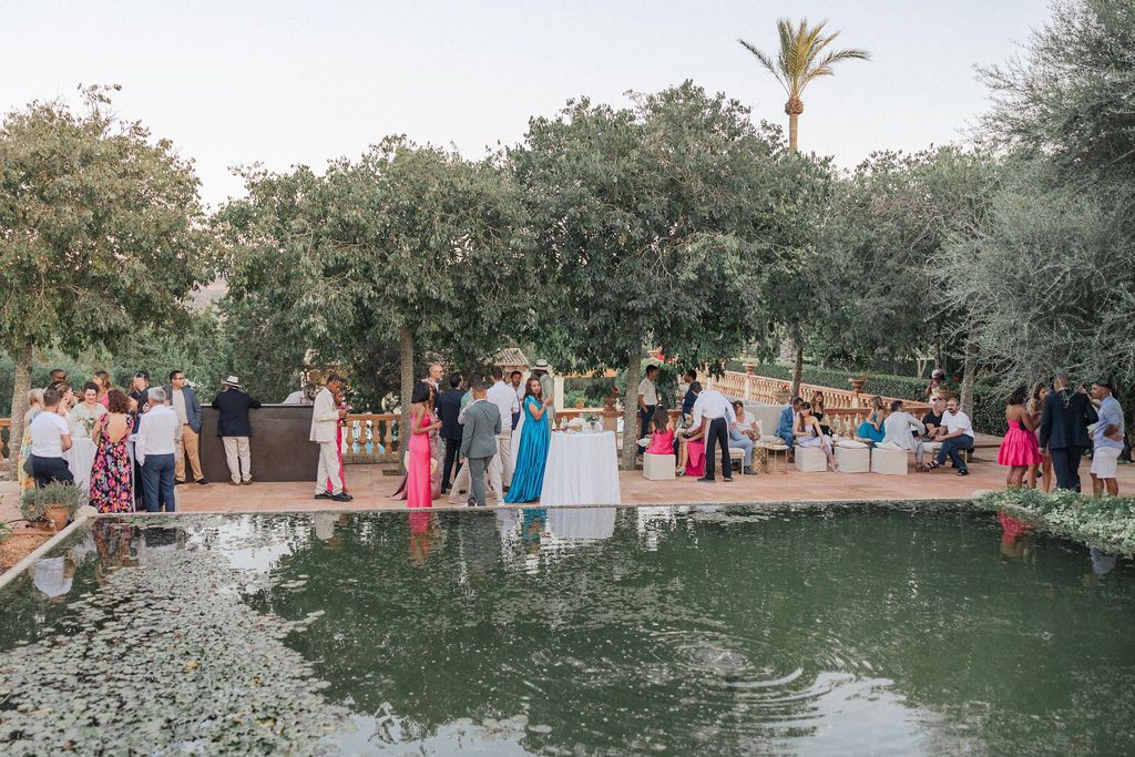 Wedding guests gathered around a garden pond during an outdoor celebration.