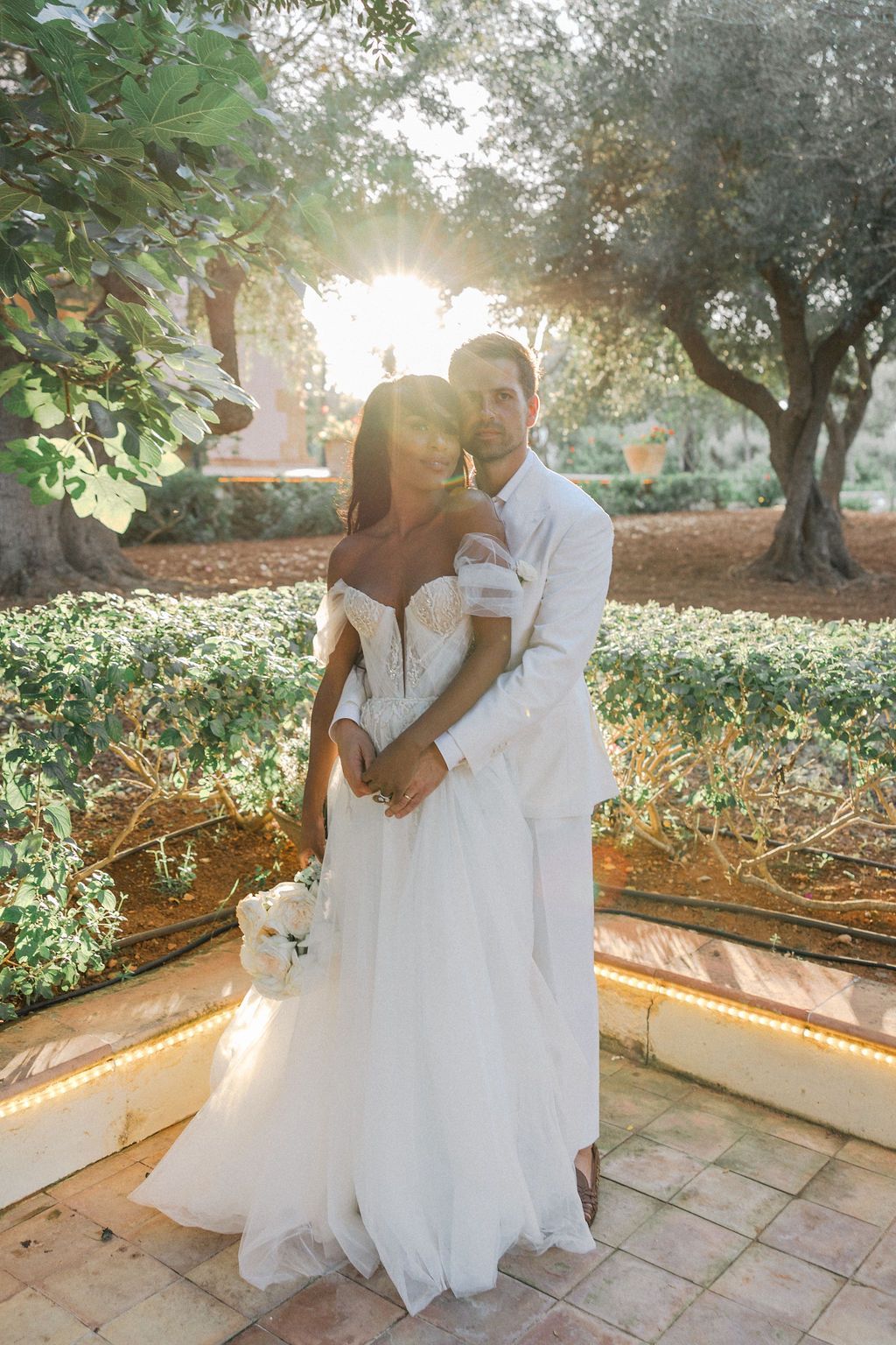 Sunlit wedding portraits in a garden with natural golden hour lighting.