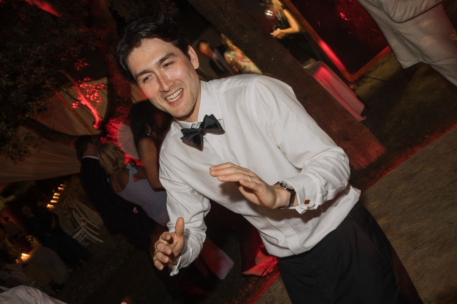 A group of people dancing and socializing at a dimly lit party venue with red lighting.