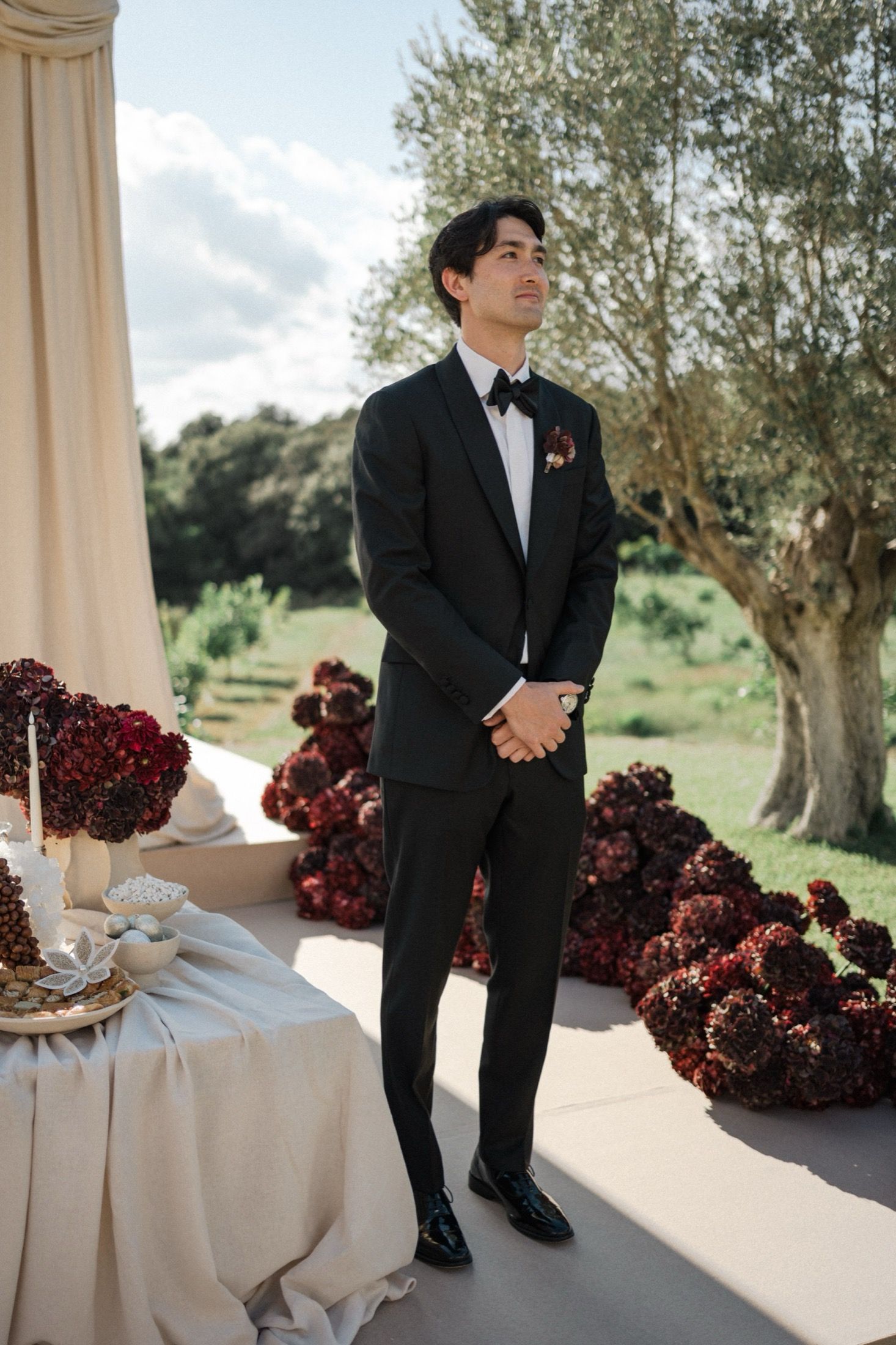 Wedding ceremony details with deep red floral arrangements and elegant decor against a light backdrop.