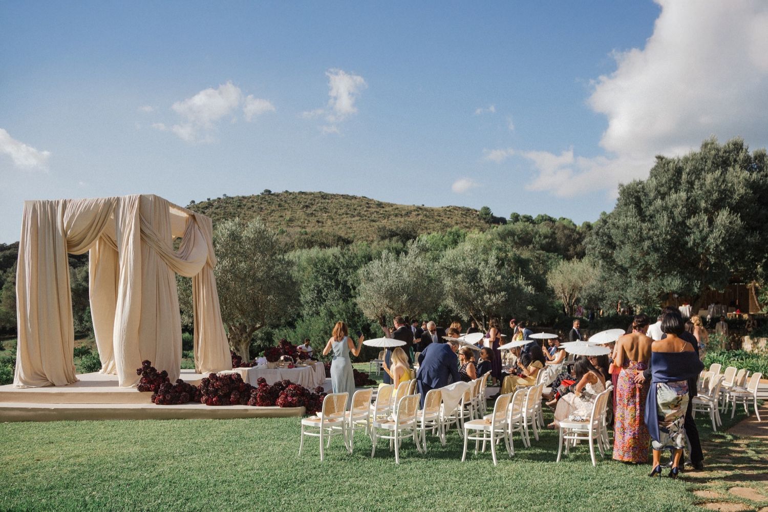 Panoramic view of an outdoor wedding ceremony setup with white chairs and floral arrangements in a scenic mountain setting.