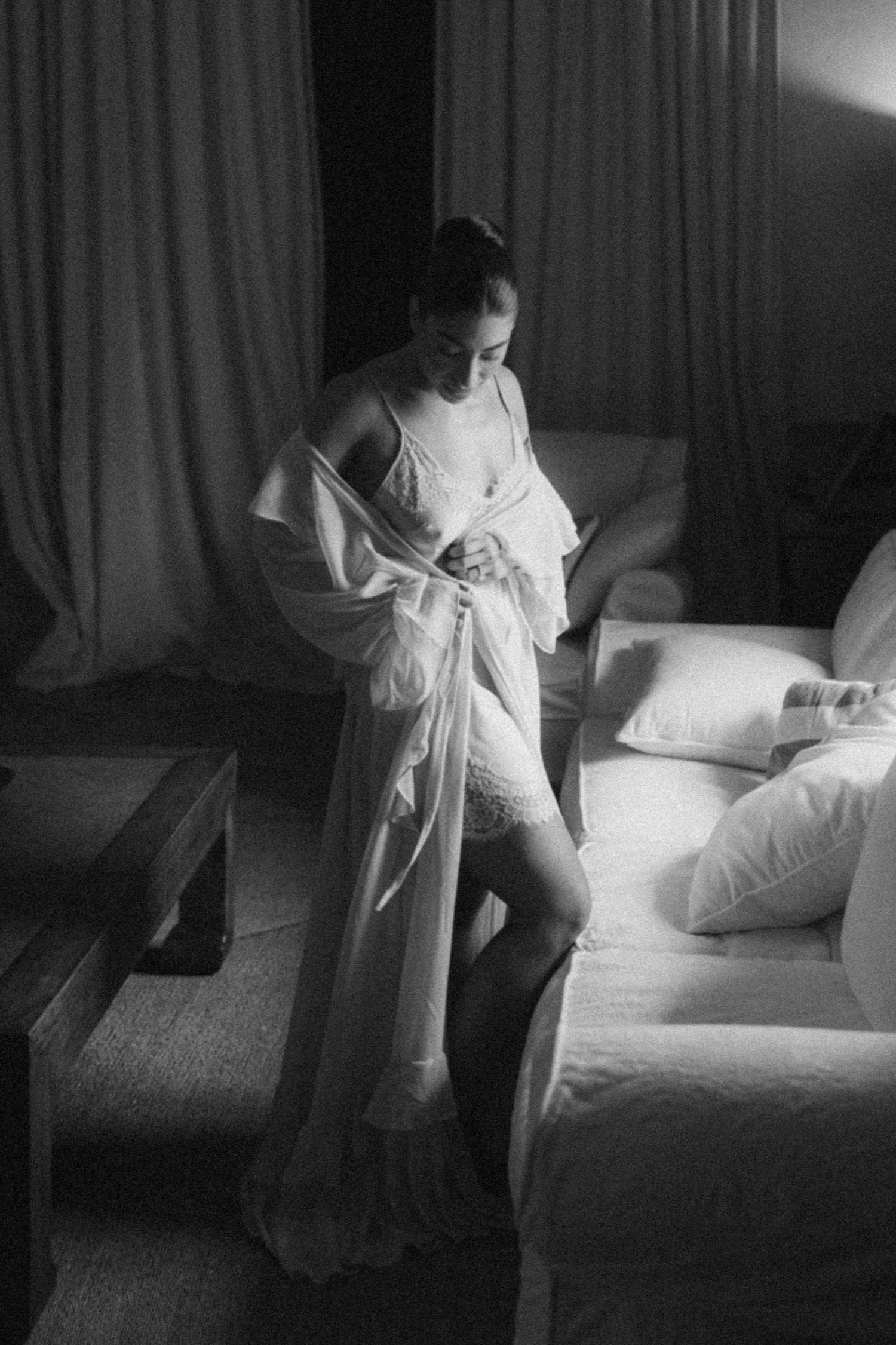 A black and white photo series shows a person in white attire making a bed in a hotel room.
