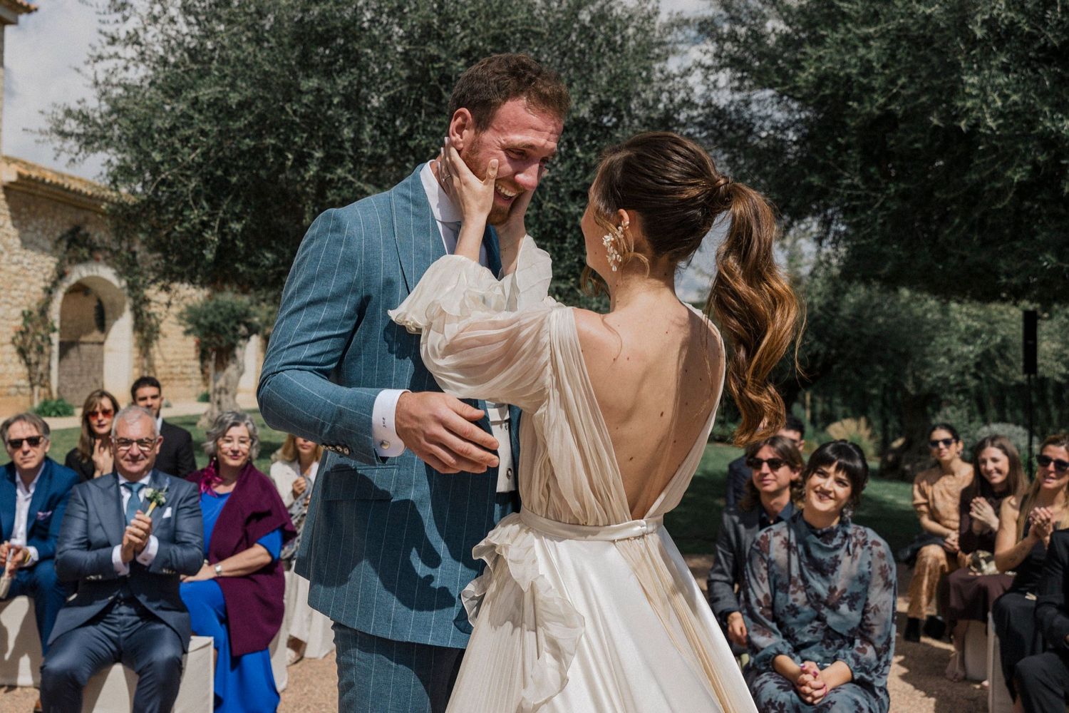 Guests celebrate and cheer during an emotional outdoor wedding ceremony in a garden setting.