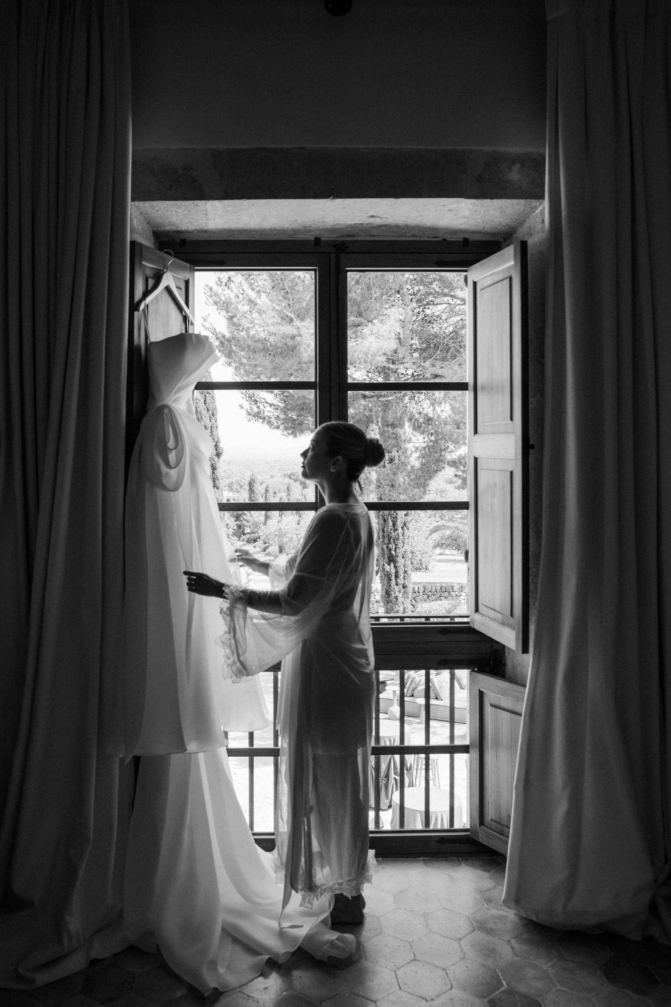 Wedding dress preparation sequence shown through window with natural light streaming in.