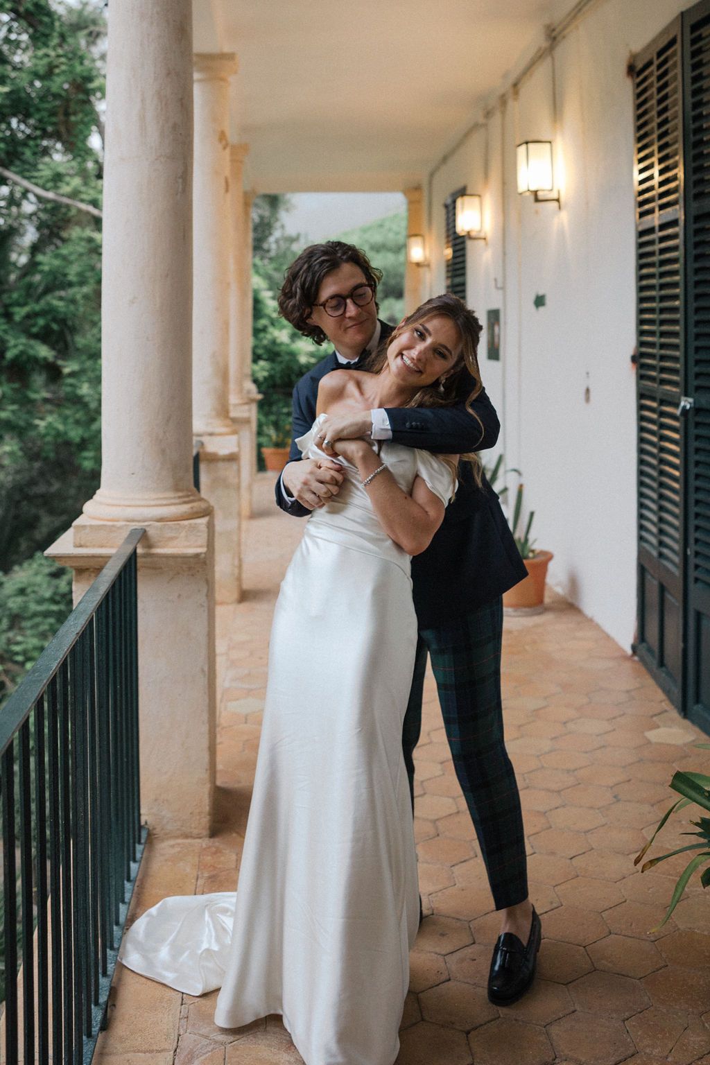 Joyful couple embracing on Mediterranean style porch with columns.