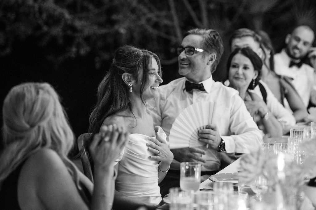 Wedding guests laughing and socializing during an outdoor evening reception.