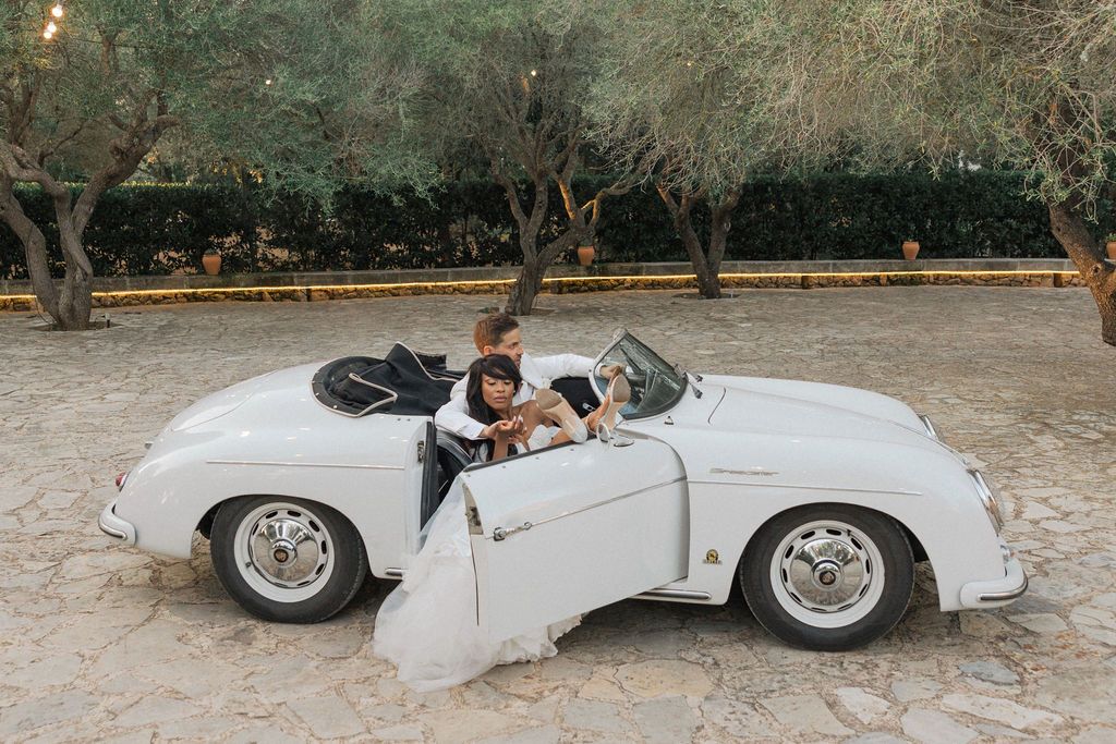 Classic white vintage convertible car parked in a rustic outdoor setting.