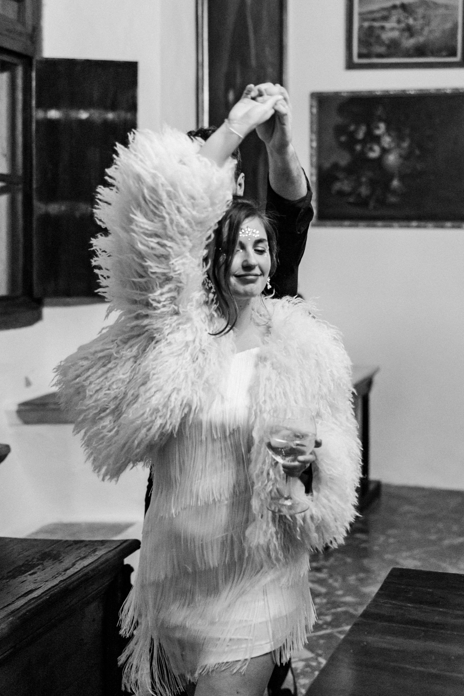 A sequence of black and white photos showing someone dancing and twirling in a feathered white costume.