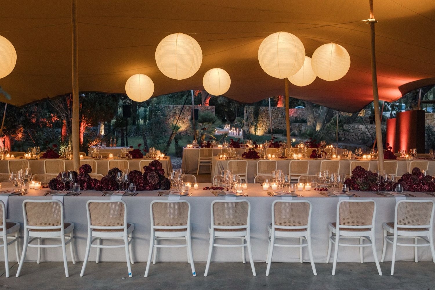 White paper lanterns illuminate a wedding reception venue with long tables and elegant decor.