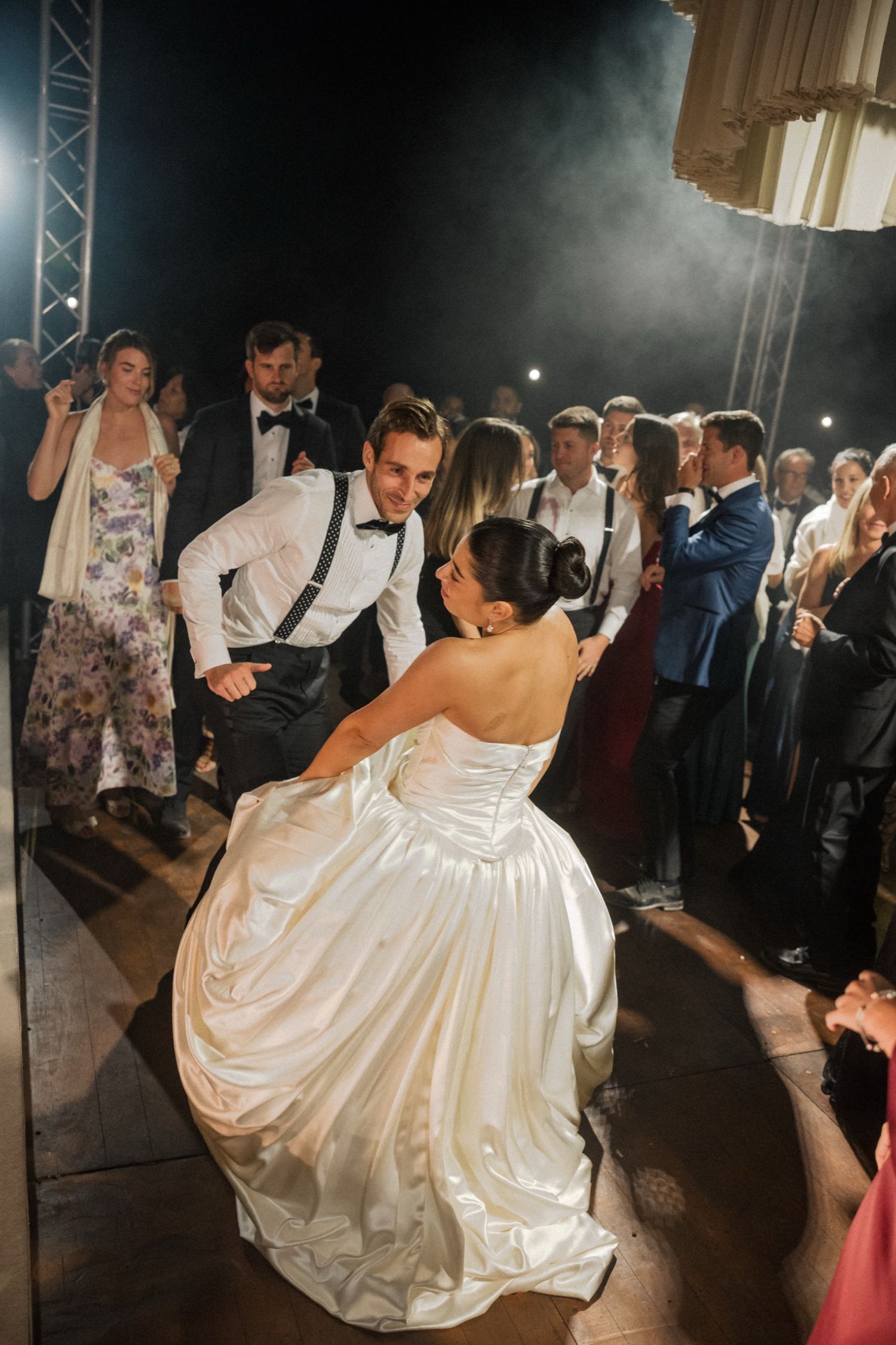 Couple dancing at their wedding reception with guests looking on as the bride's white ballgown dress twirls on the dance floor.