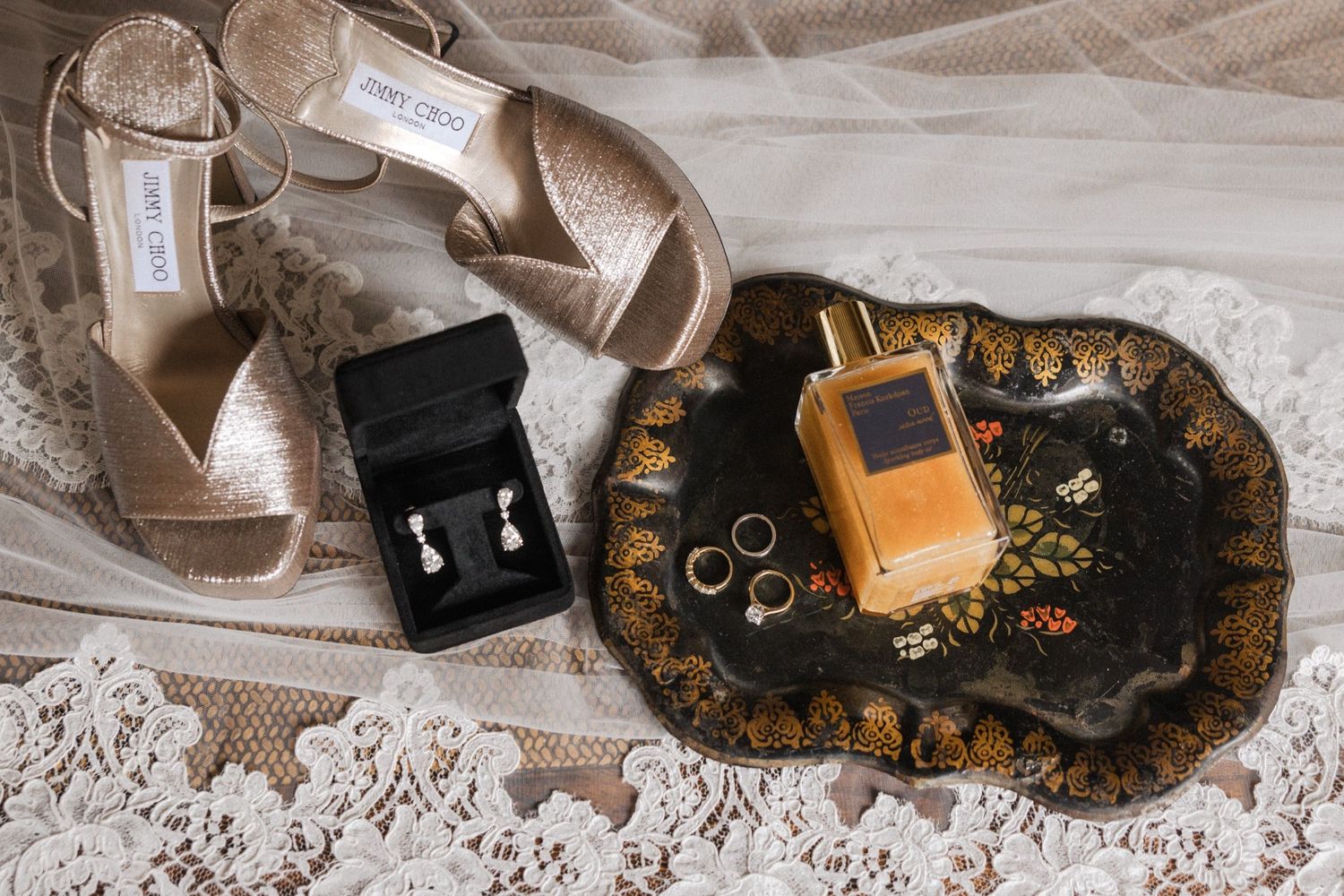 Wedding accessories including rings, shoes, and jewelry arranged on delicate lace fabric.