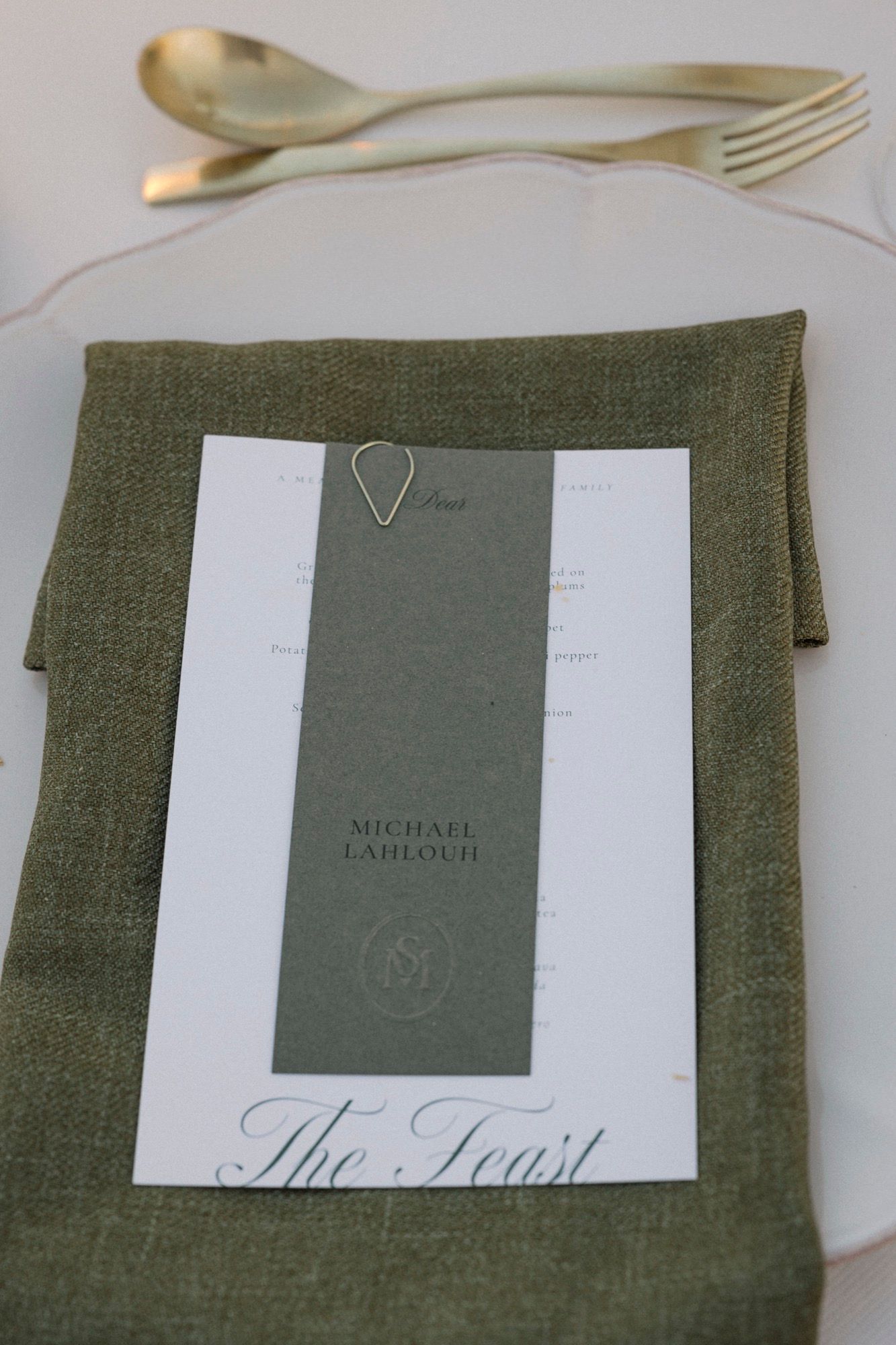 Olive green linen napkin with elegant wedding menu card and place setting.