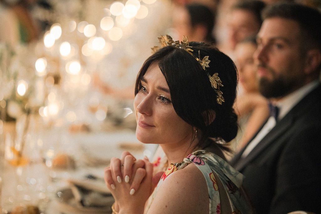 Wedding guests seated at an elegant candlelit reception table during dinner.
