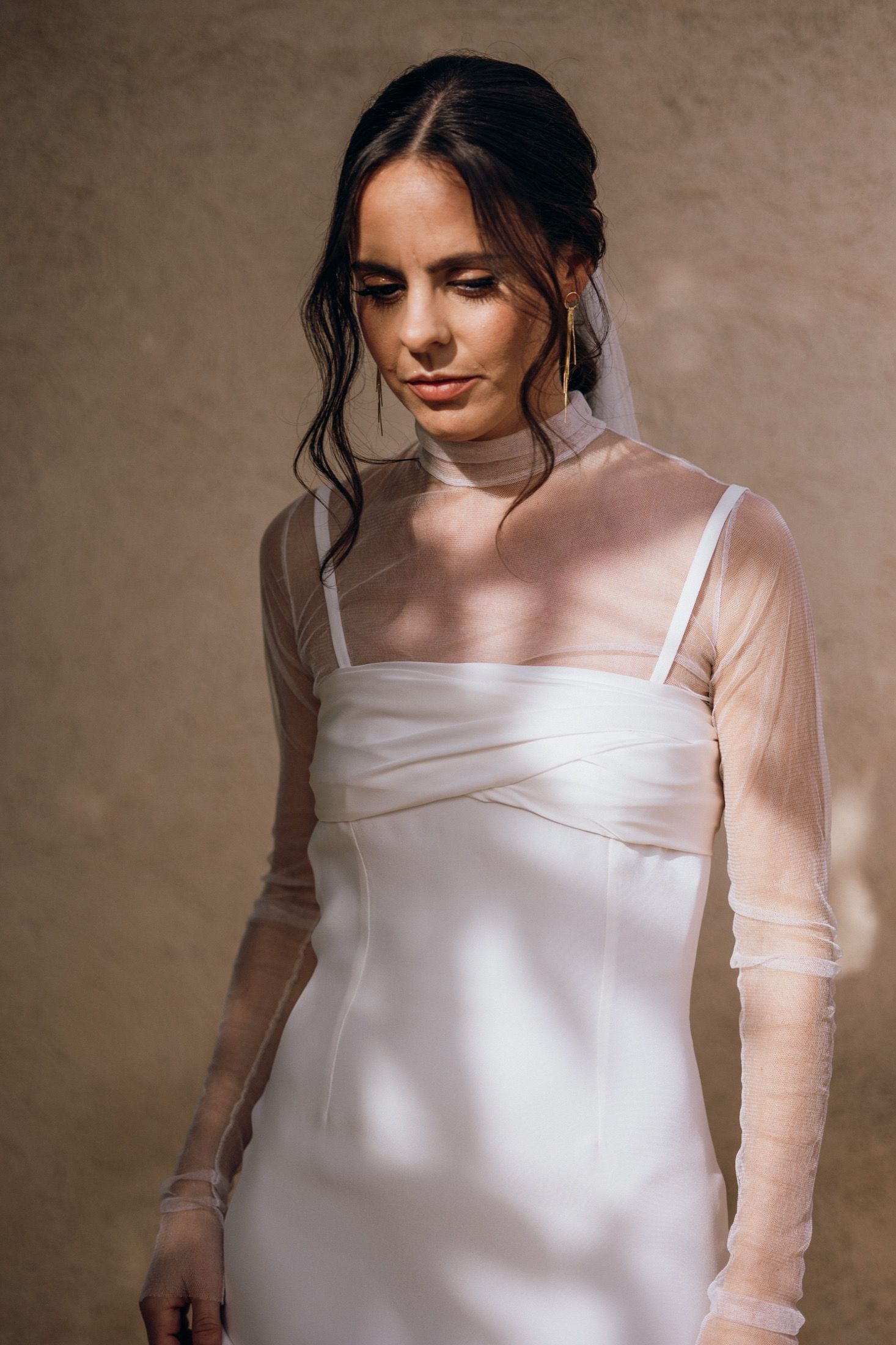 A white silk wedding dress with sheer mesh sleeves shown in a series of elegant detail shots against a neutral background.