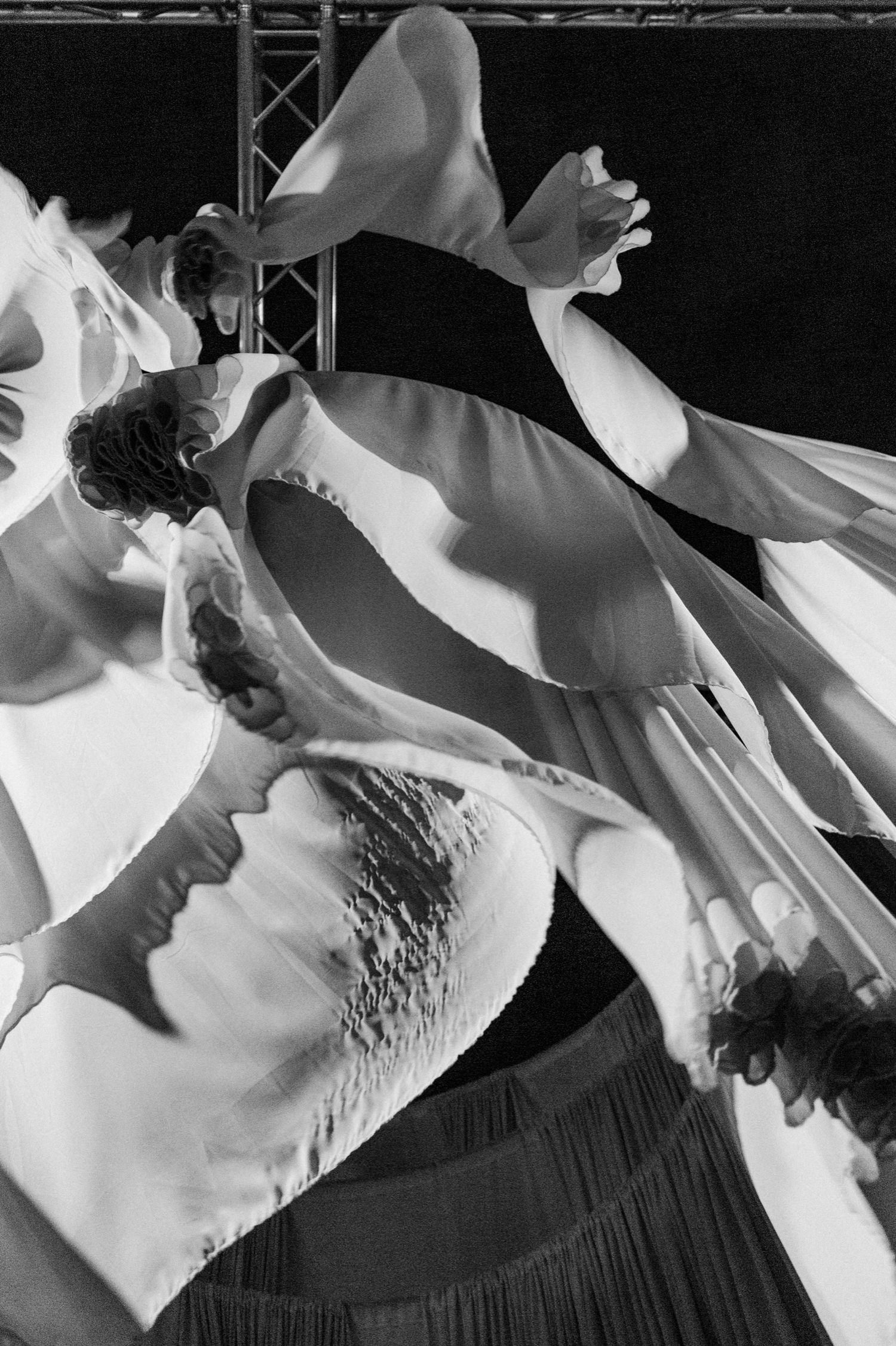Black and white close-up photograph showing abstract shadows and textures of folded fabric or paper creating dramatic contrast.