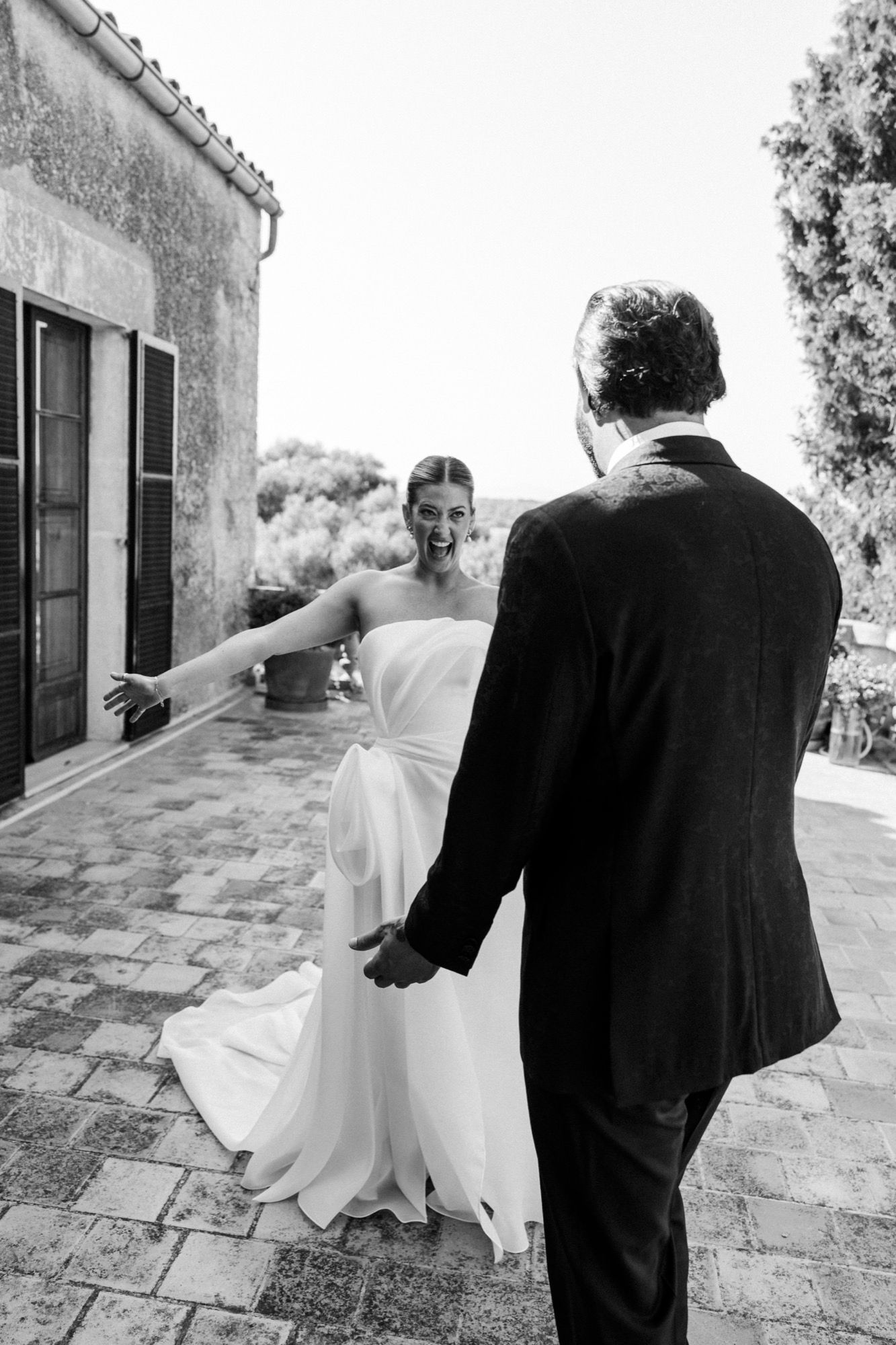 Wedding couple walking along a Mediterranean stone patio with classic architecture.