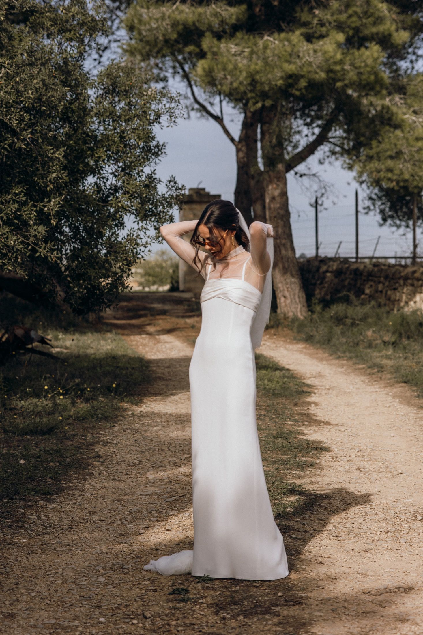 A sequence of photos showing a bride in a white dress walking along a rustic dirt path lined with trees.