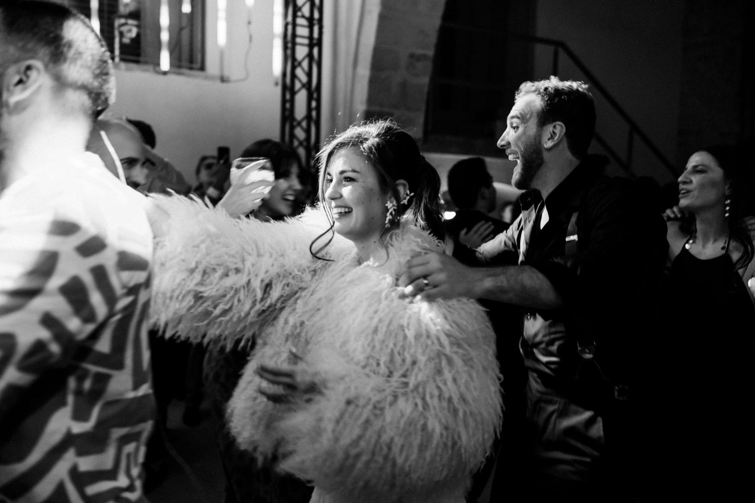 Black and white photo of people dancing and celebrating at a glamorous party, with feathered accessories visible.