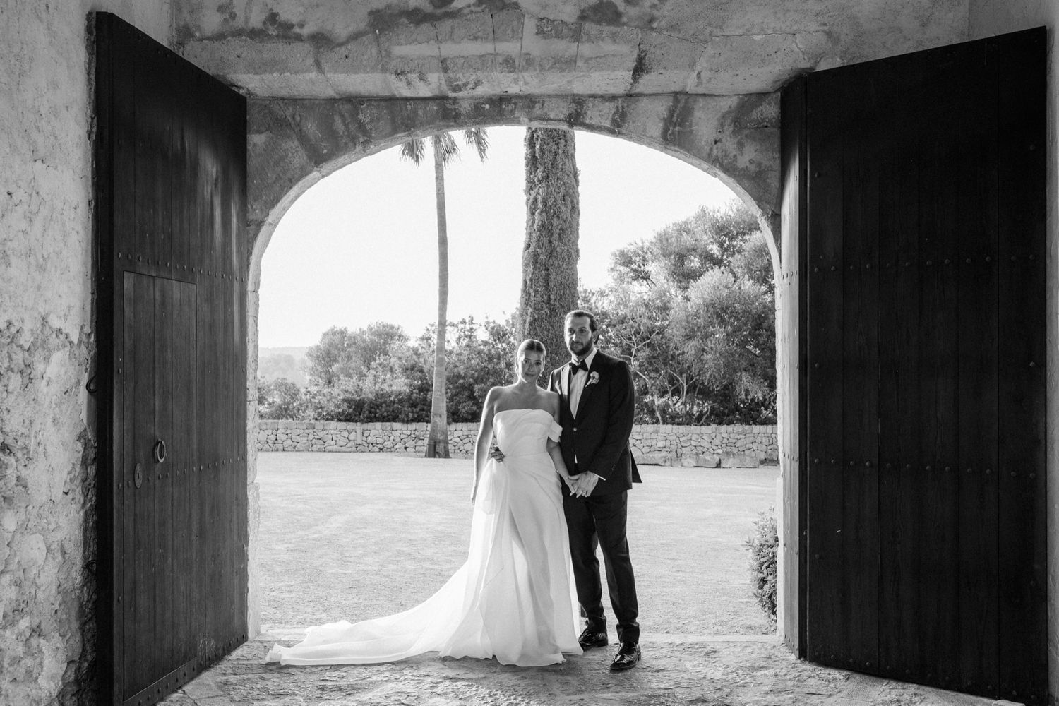Black and white archway frames romantic wedding couple silhouette.