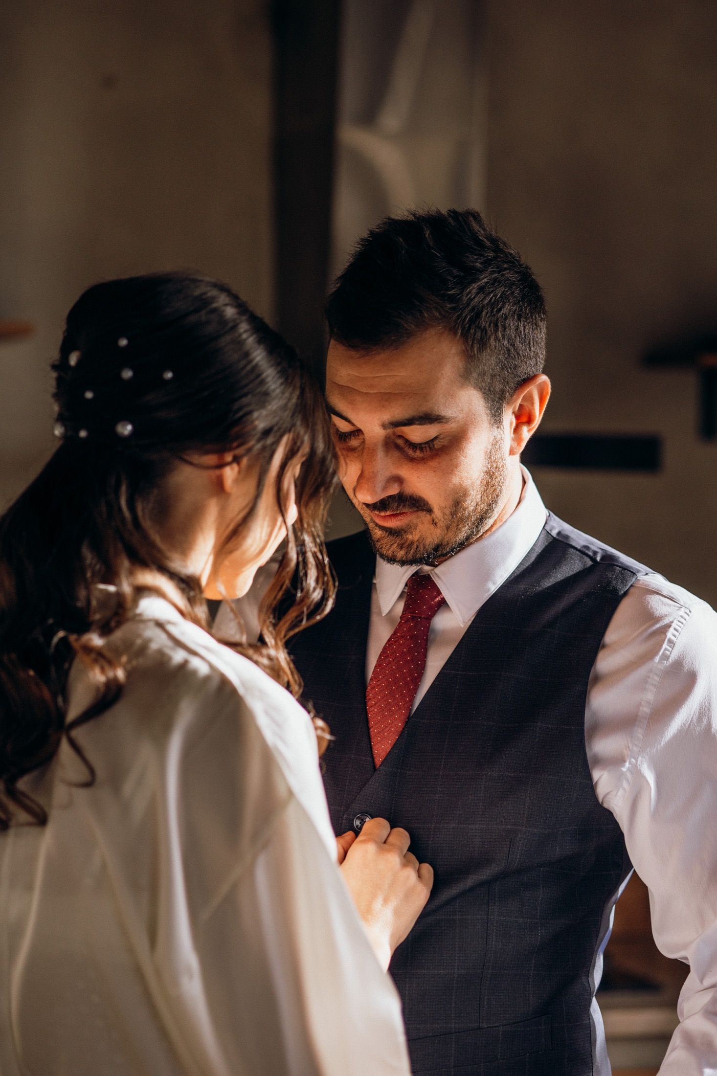 A tender moment between a couple in wedding attire, with warm lighting creating an intimate atmosphere.