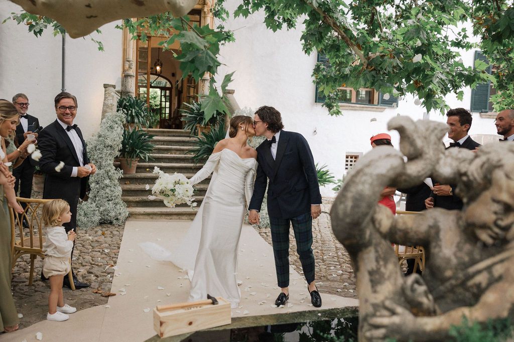 Wedding celebration candid moments captured in garden setting with stone architecture.