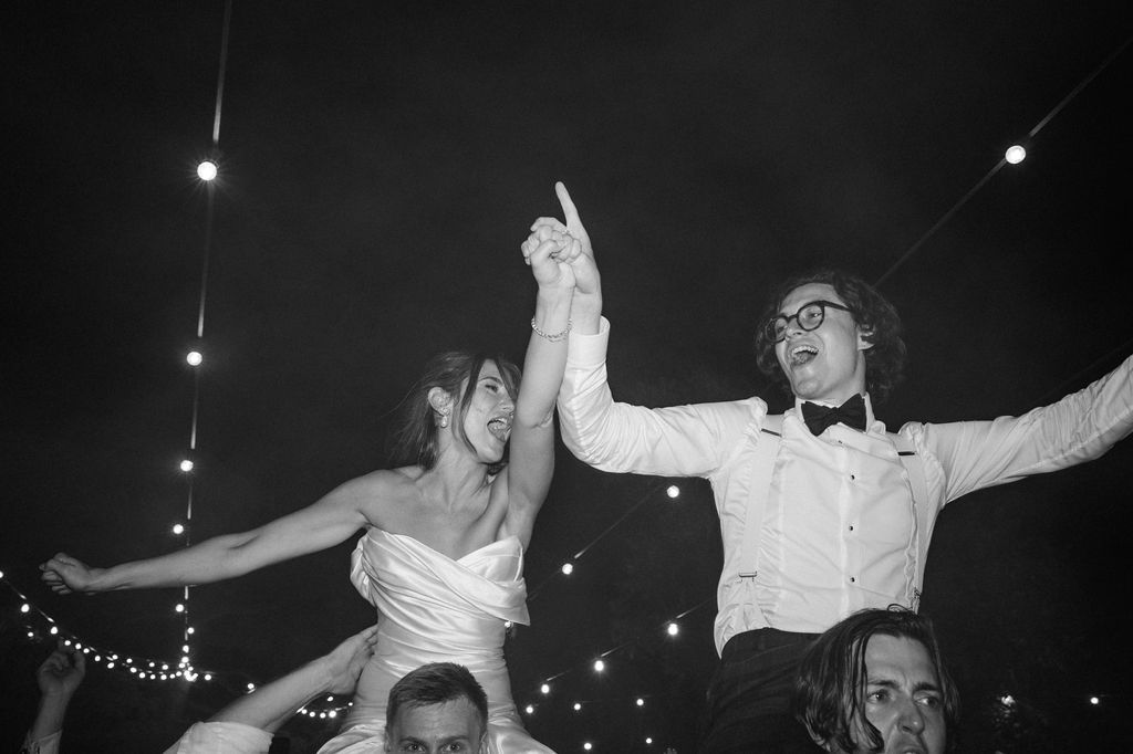 People dancing and celebrating under twinkling lights at an outdoor nighttime event.