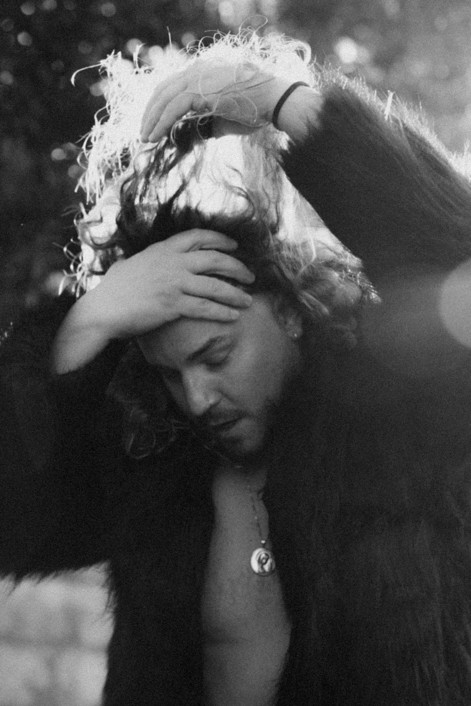 A moody black and white photo of a person with long hair holding their head in an emotional pose.