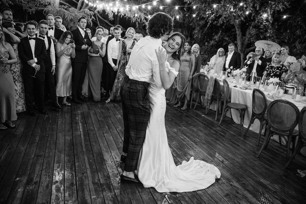 Black and white photo of wedding reception dancing on rustic wooden deck.