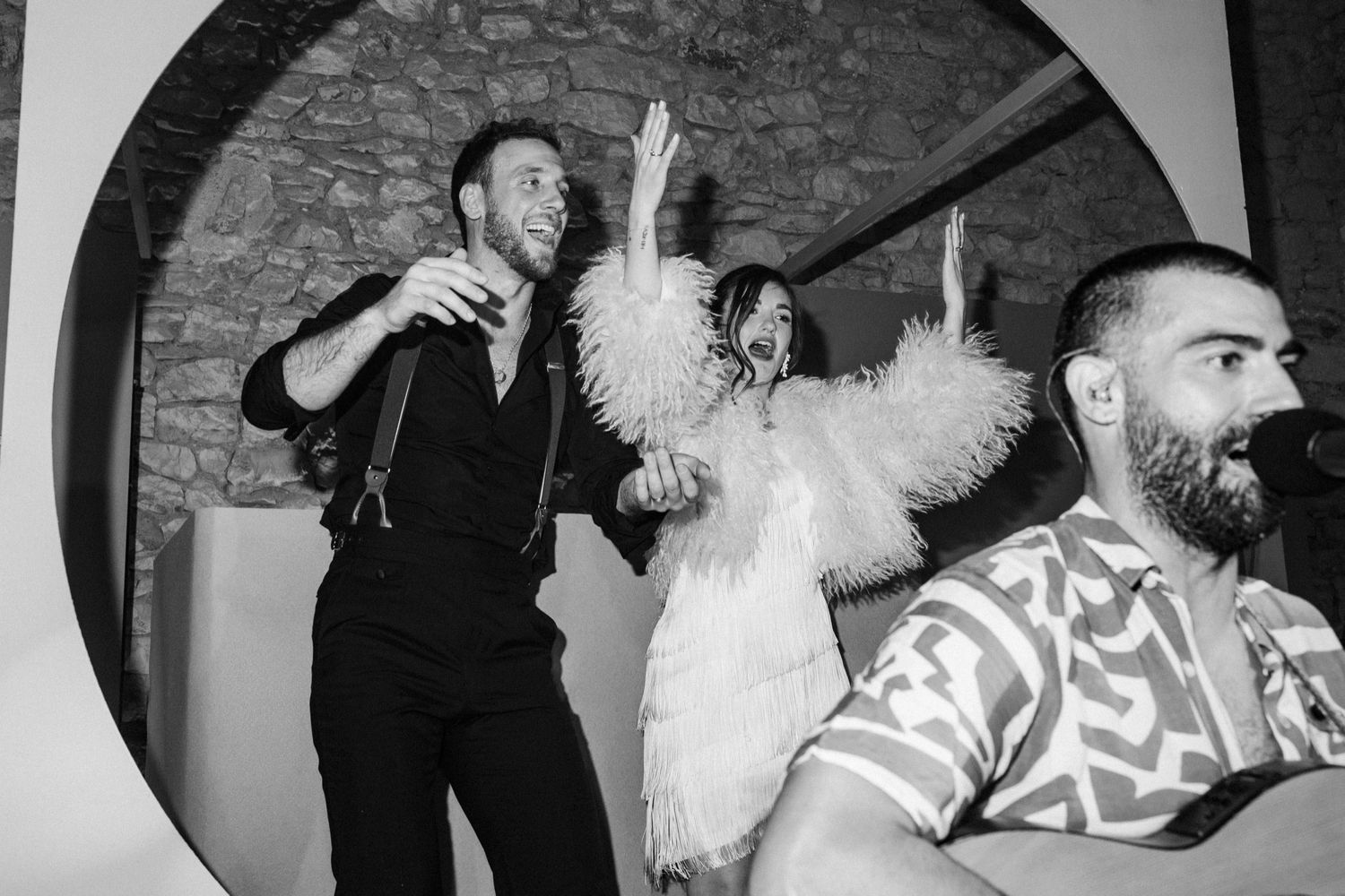 Black and white photograph of people dancing and celebrating at a lively party or social gathering.