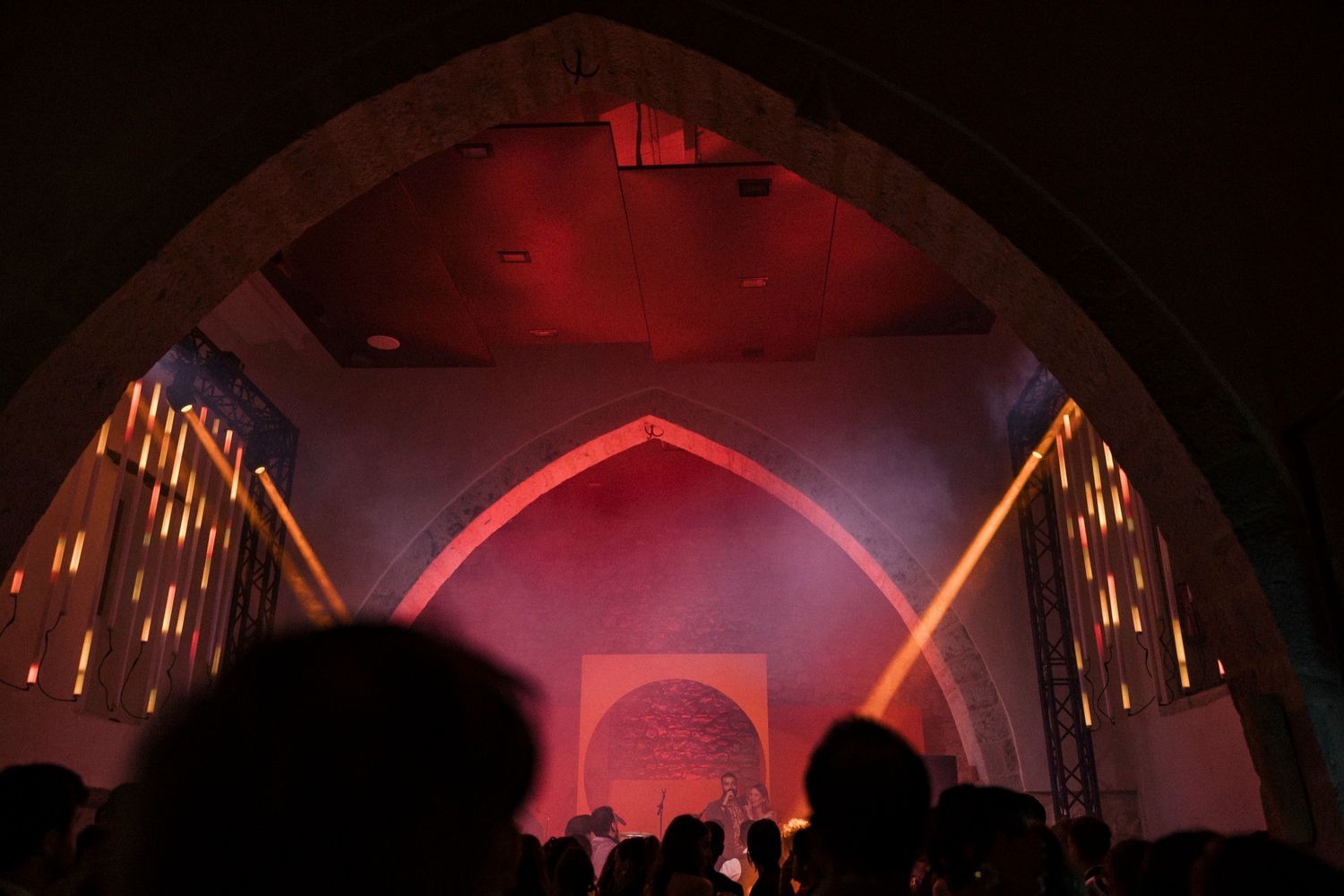 Concert stage illuminated with dramatic red lighting and fog effects creates an atmospheric performance environment.