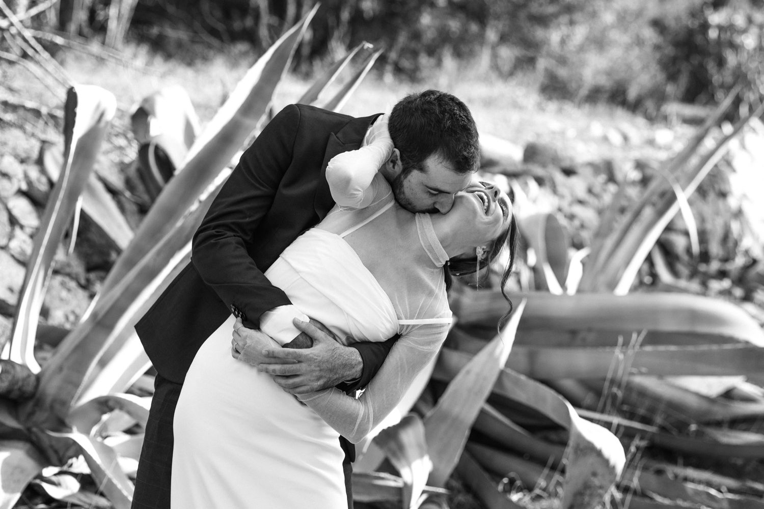 A black and white collage of intimate wedding moments showing couples embracing in romantic outdoor settings.