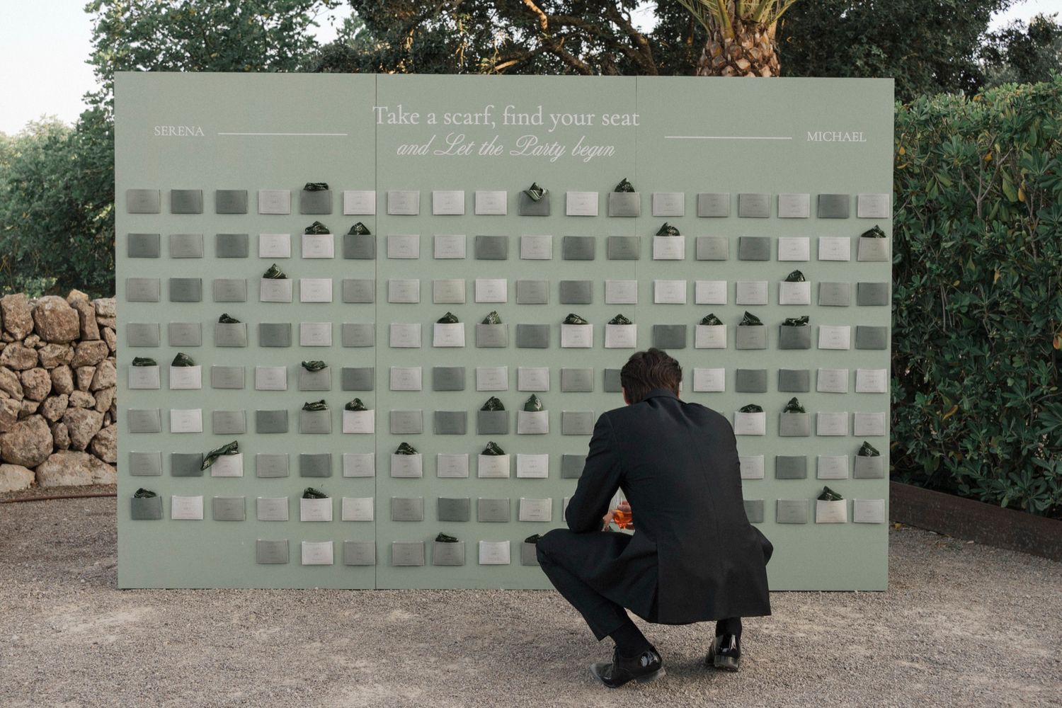 Modern wedding photo display wall with minimalist grid design and green backdrop.