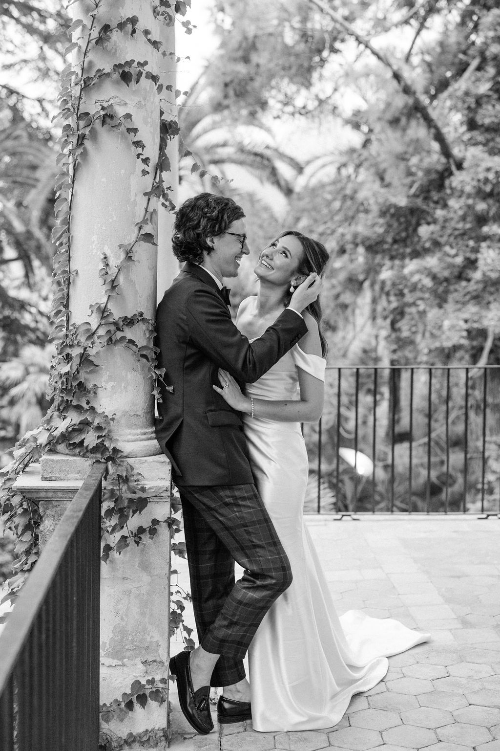 Black and white wedding portraits showing playful moments between columns.