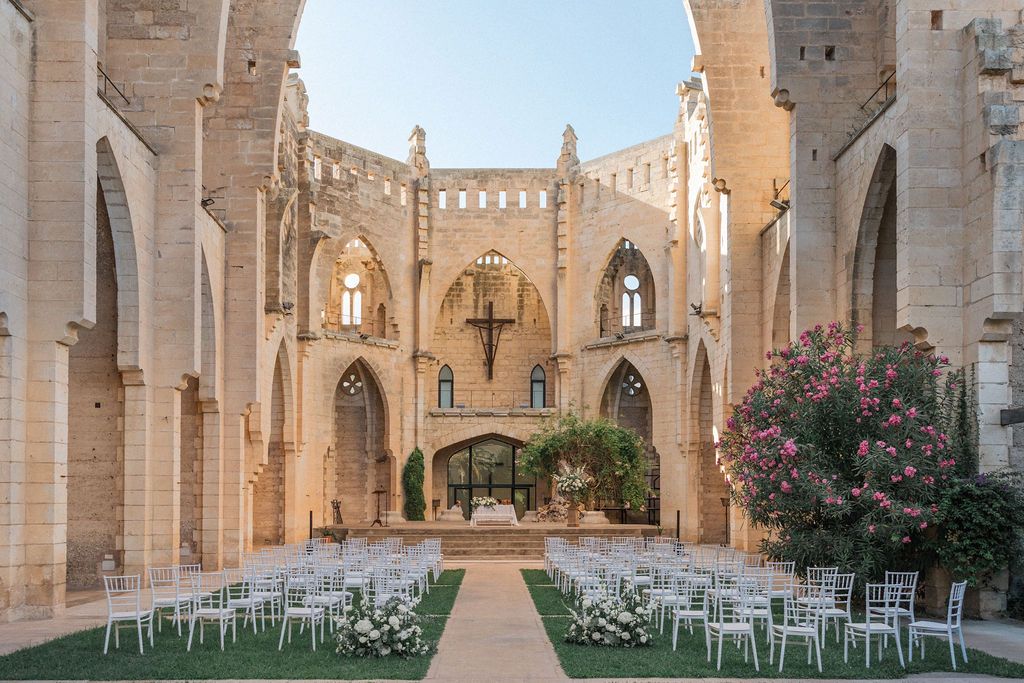 Gothic stone cathedral courtyard with symmetrical arches and elegant ceremony setup.