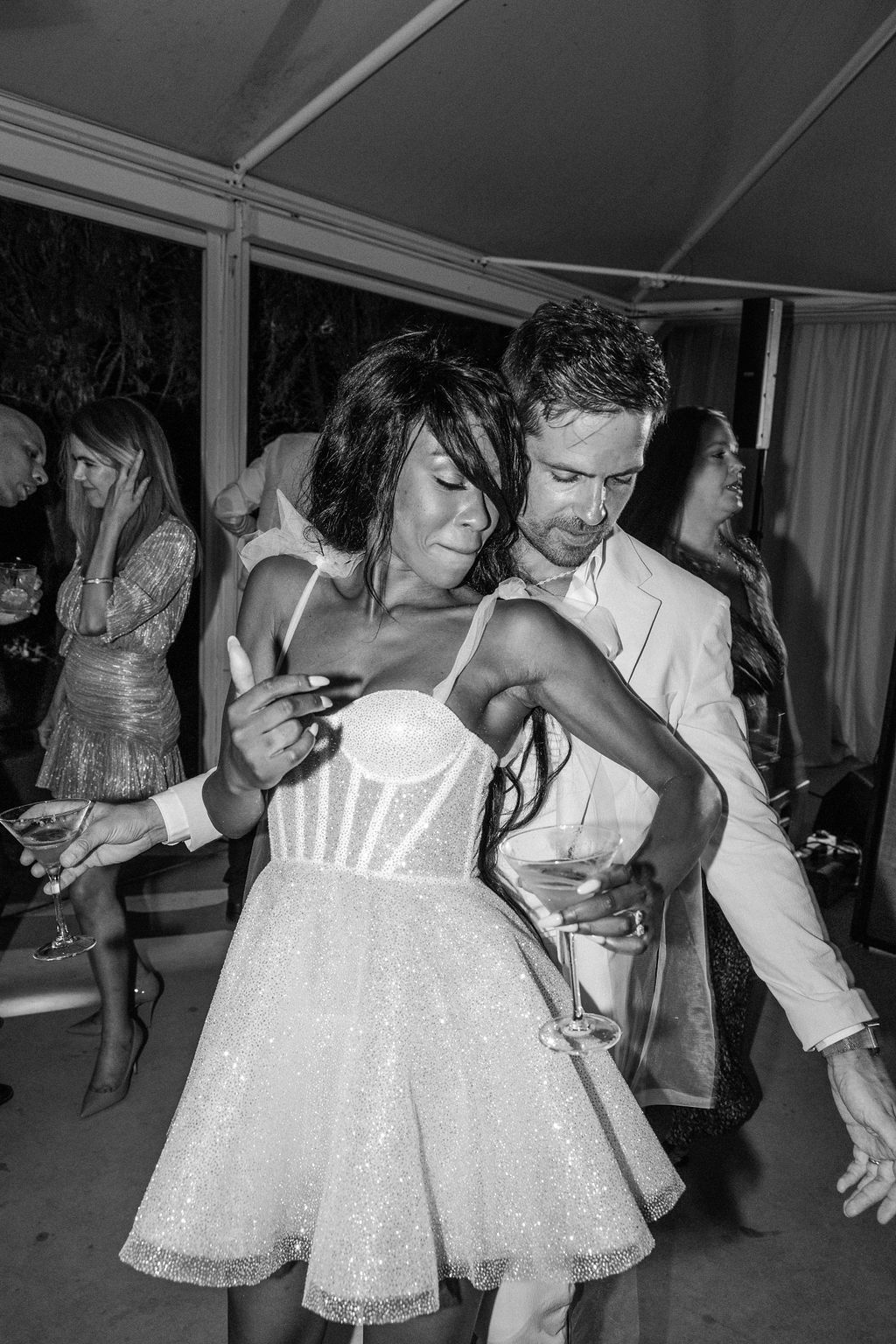 Wedding guests in formal attire dance and celebrate at an indoor reception.
