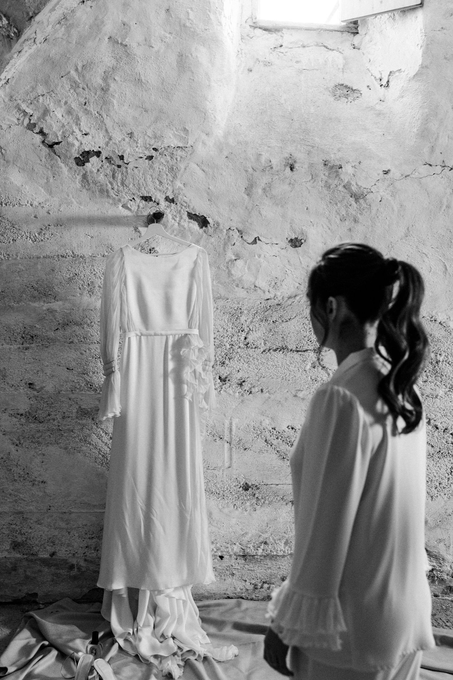 A series of black and white photos showing a figure in white fabric against a textured wall creating dramatic shadows.