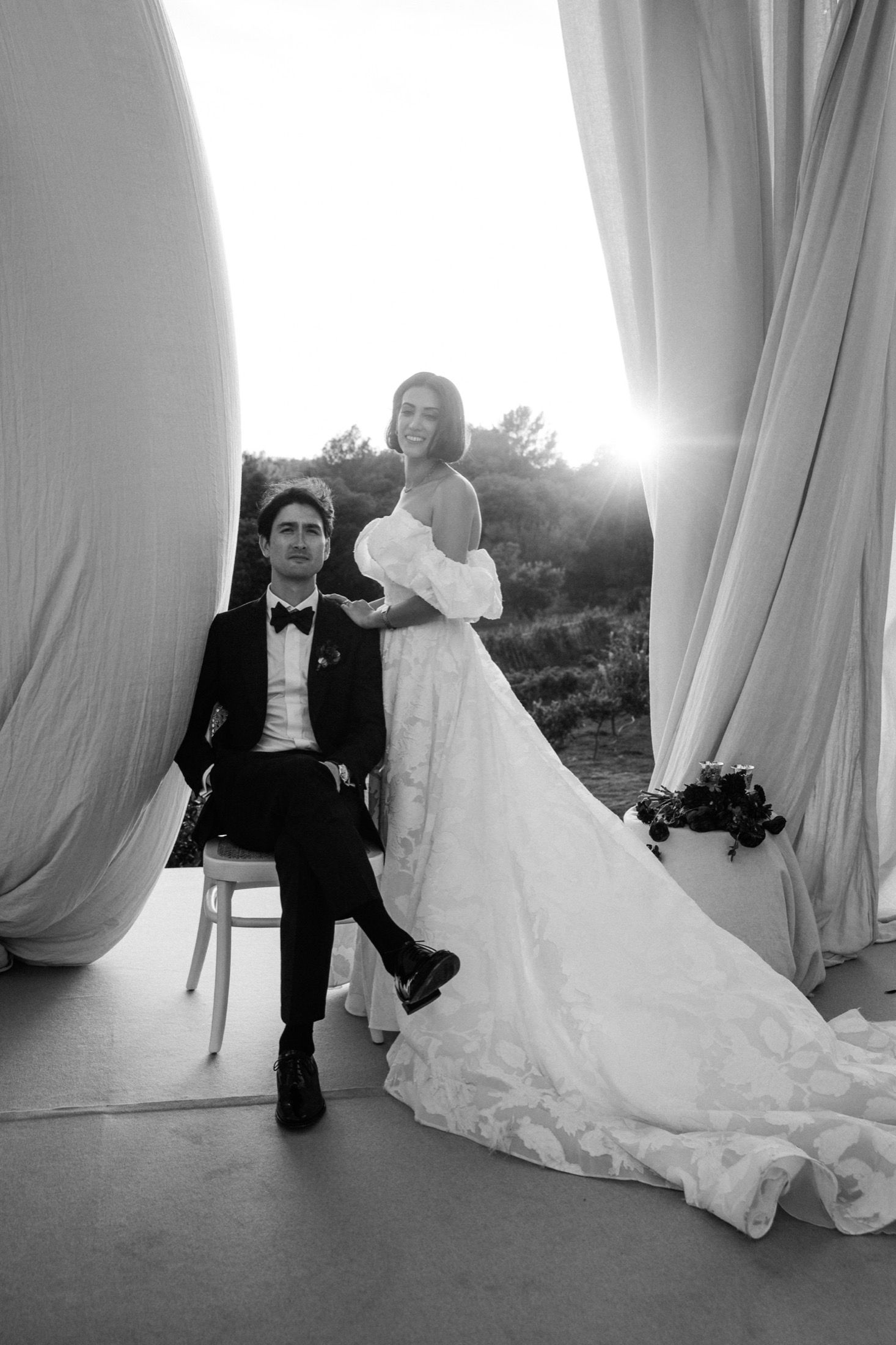 A romantic black and white wedding photo sequence showing a couple posing elegantly with flowing white curtains.