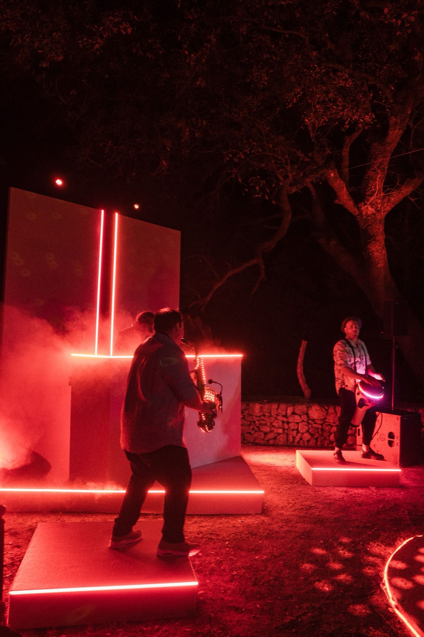 People practicing lightsaber combat in a dark outdoor setting illuminated by glowing red lights.