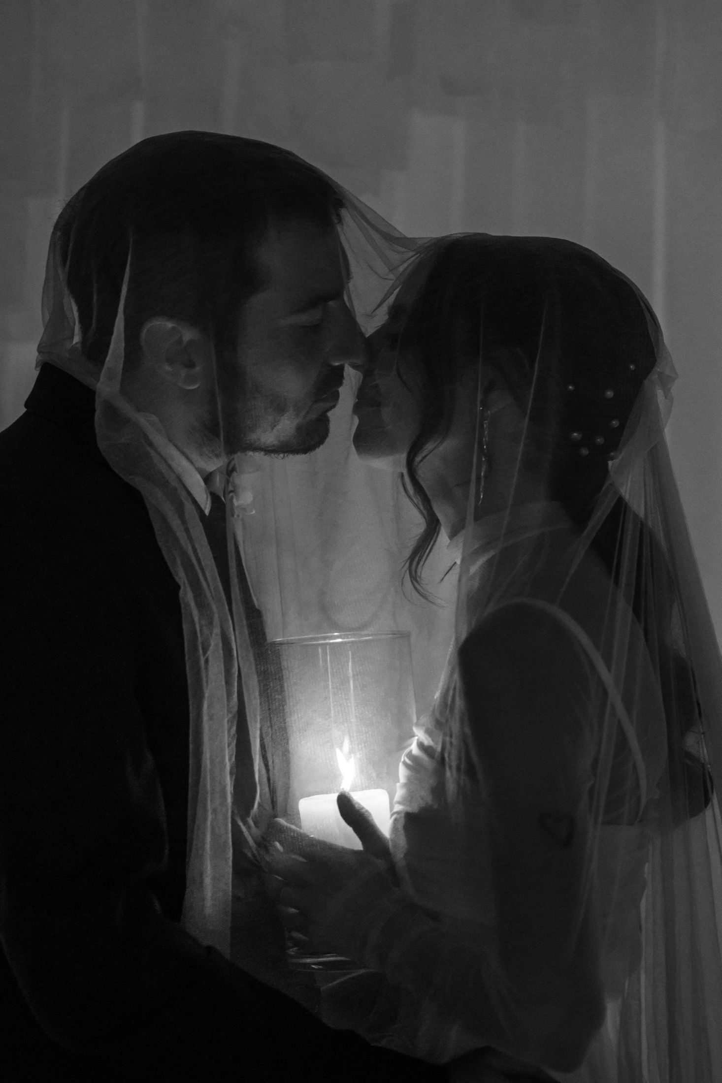 A sequence of dark, moody black and white photos showing a candlelit scene through sheer fabric creating an ethereal effect.