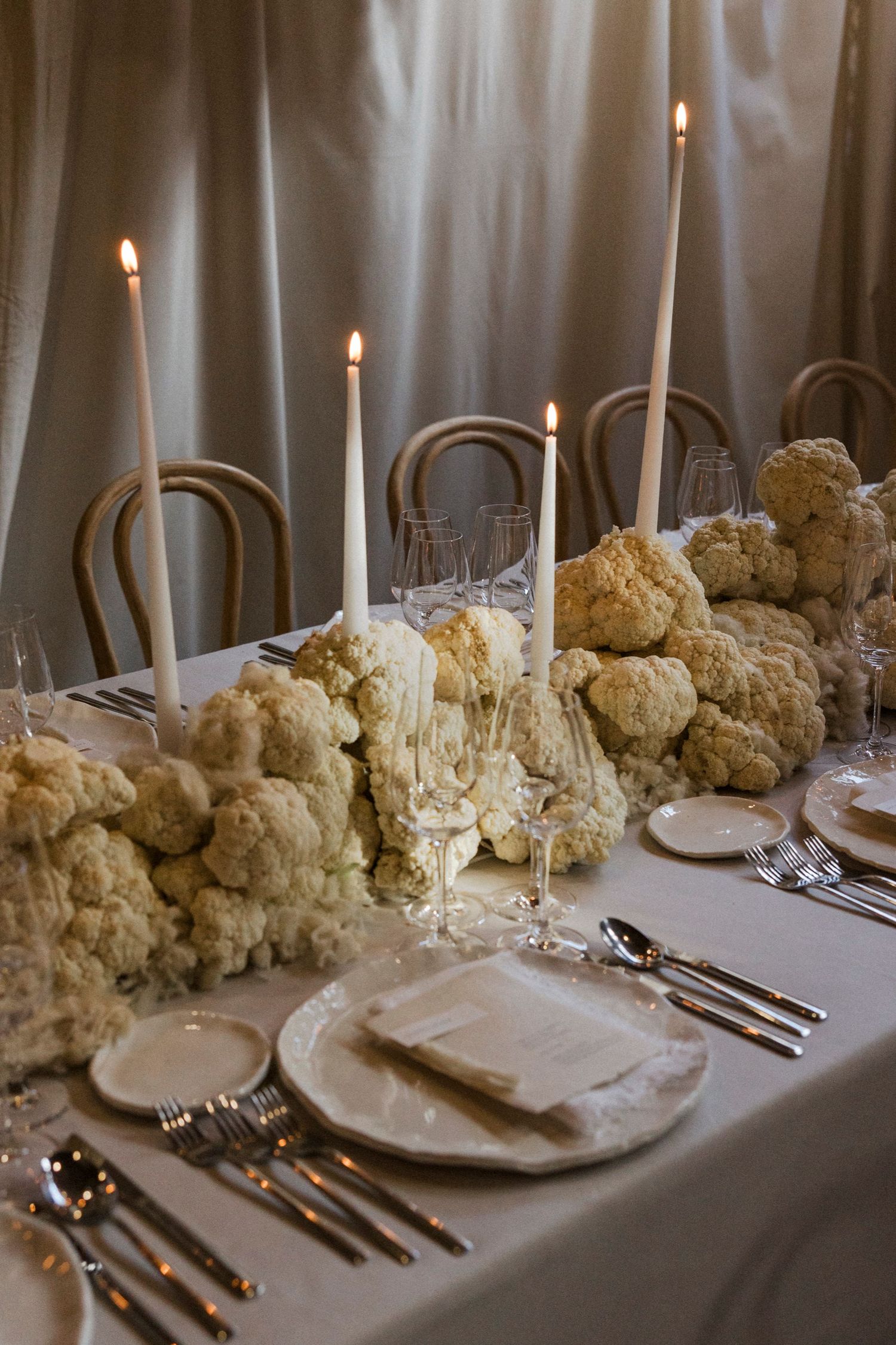 Romantic wedding reception table with cream floral arrangements and taper candles.