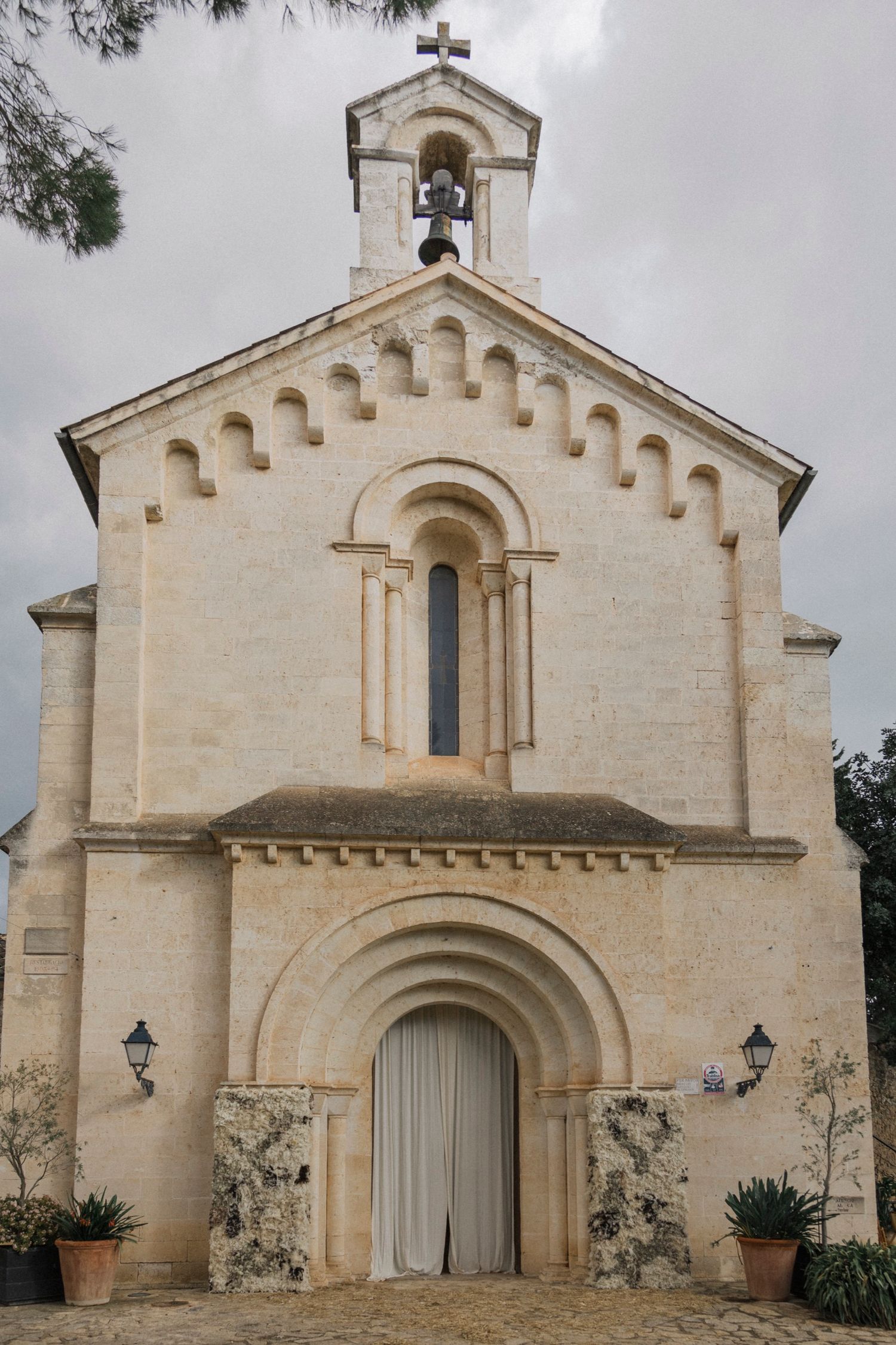 Exterior of a Romanesque stone church with arched entrance and battlements.