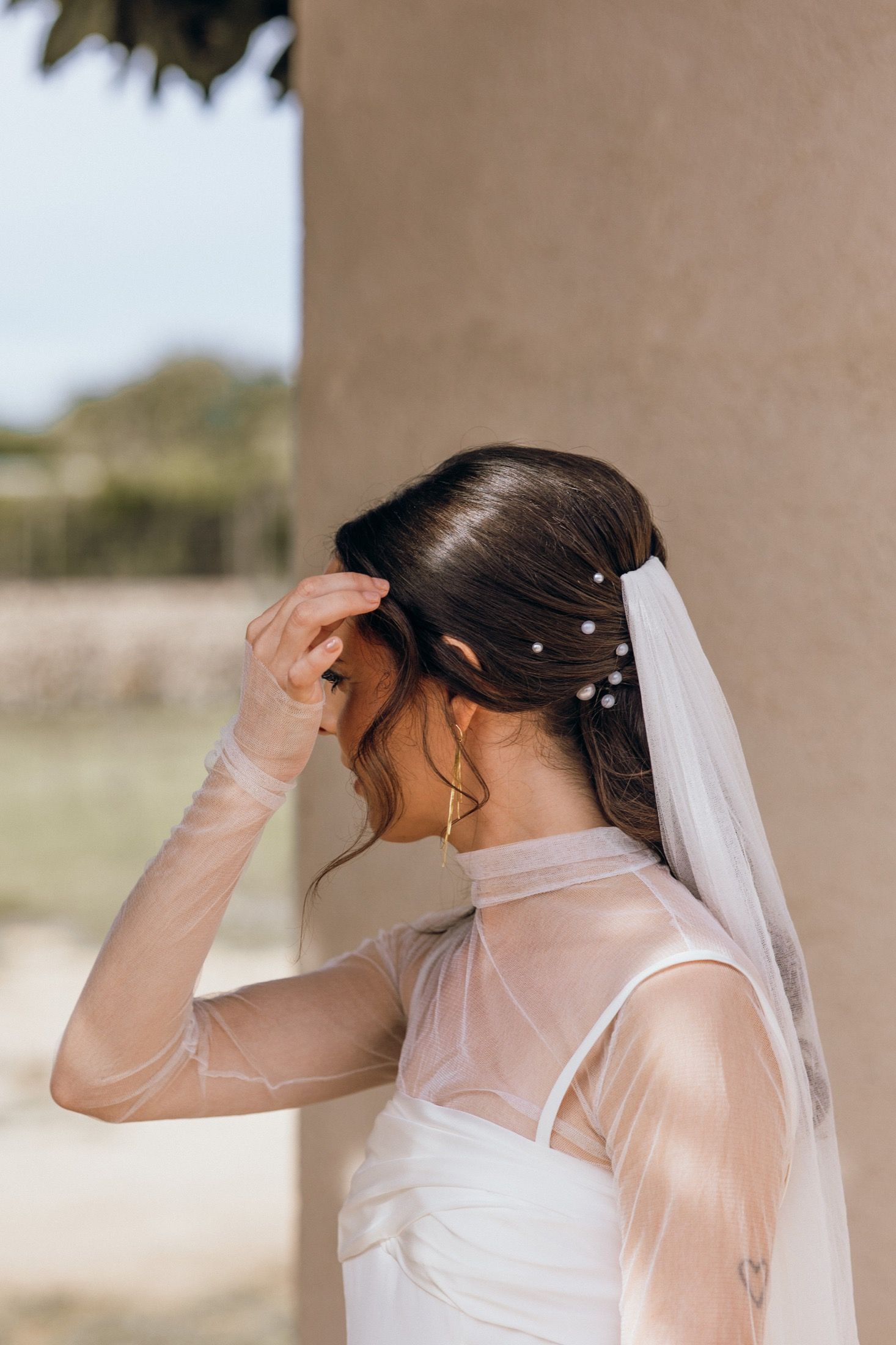 A bride adjusts her white veil against a beige wall in a sequence of four similar poses.