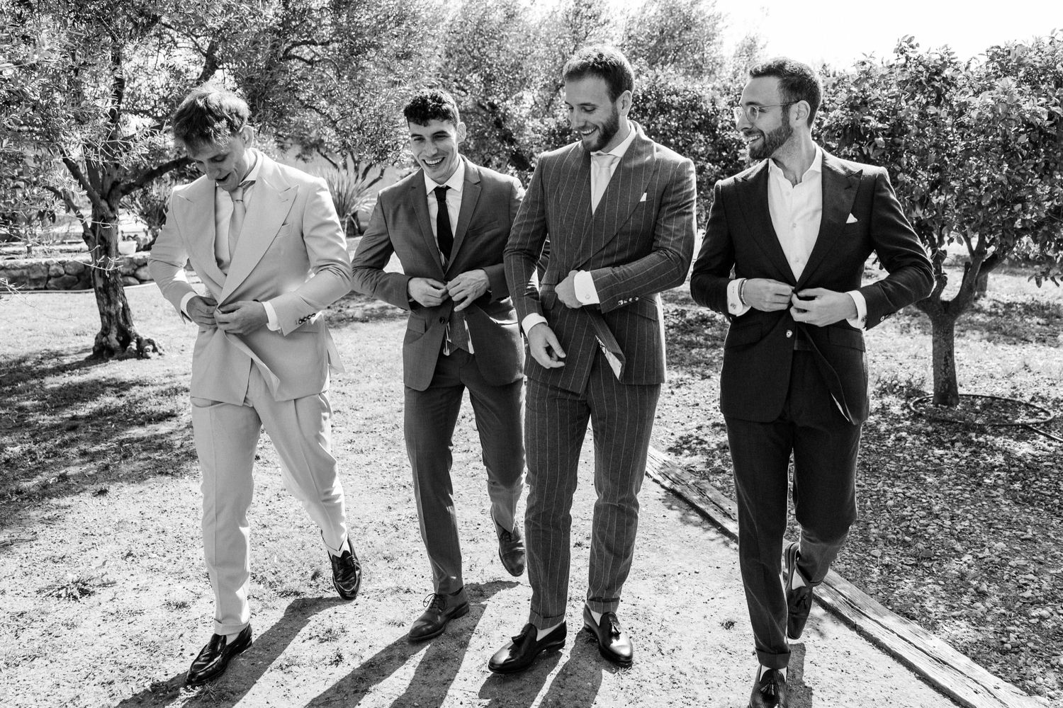 Four men in stylish suits walking together outdoors in a black and white vintage photograph.