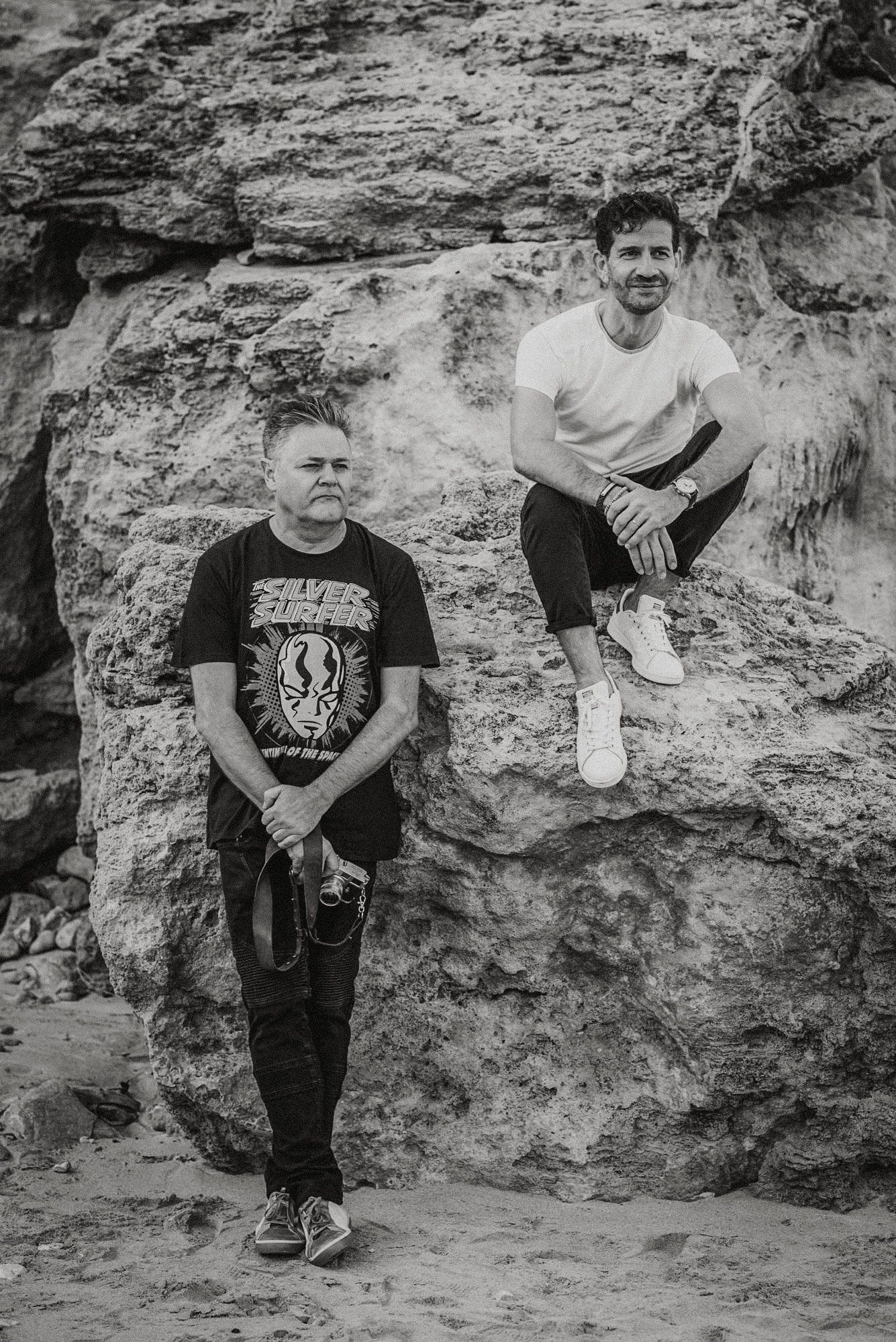 A series of casual portraits taken against a rocky wall backdrop in black and white.