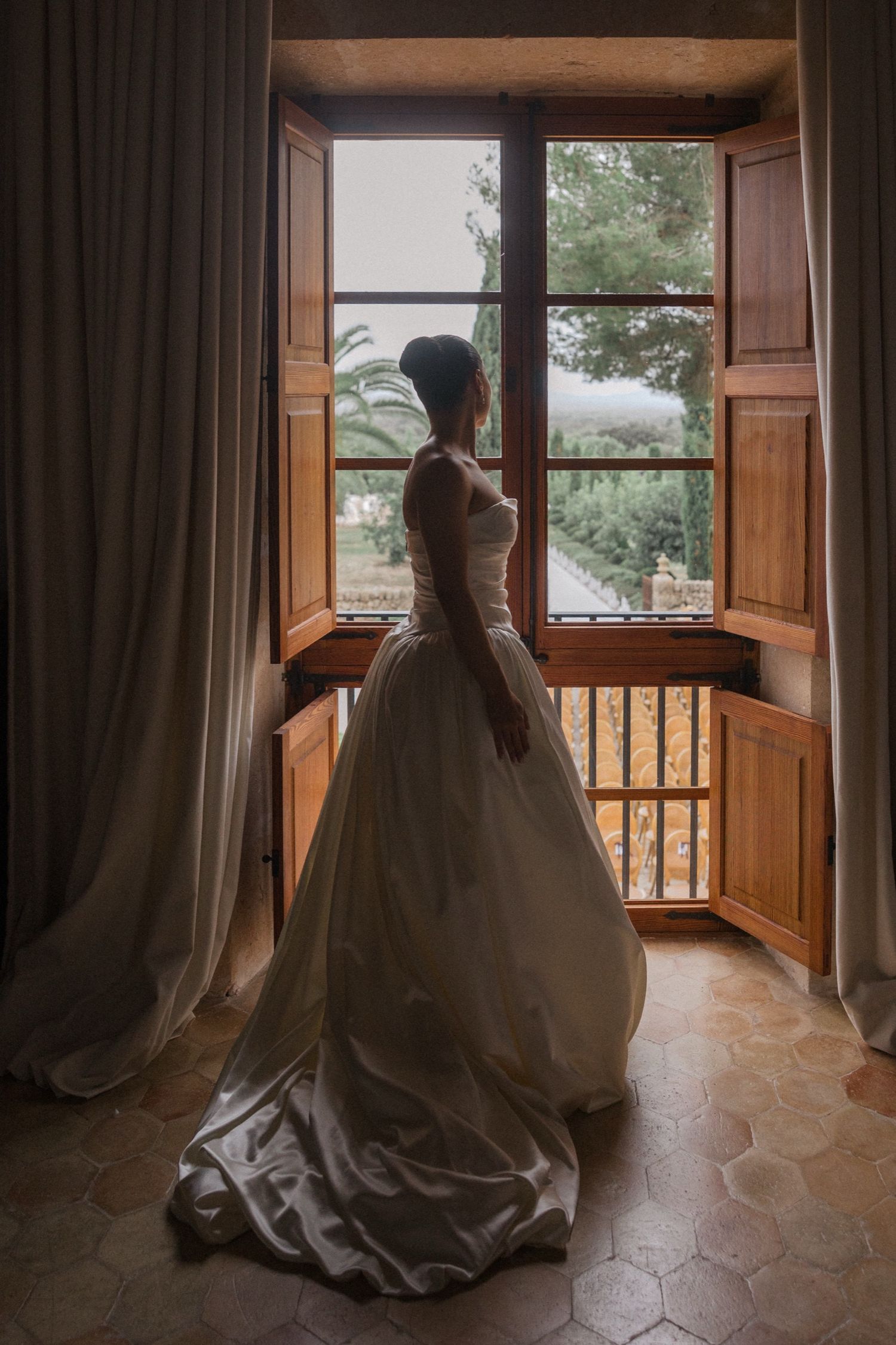A series of artistic photos showing a wedding dress silhouette against large windows in a rustic wooden room.