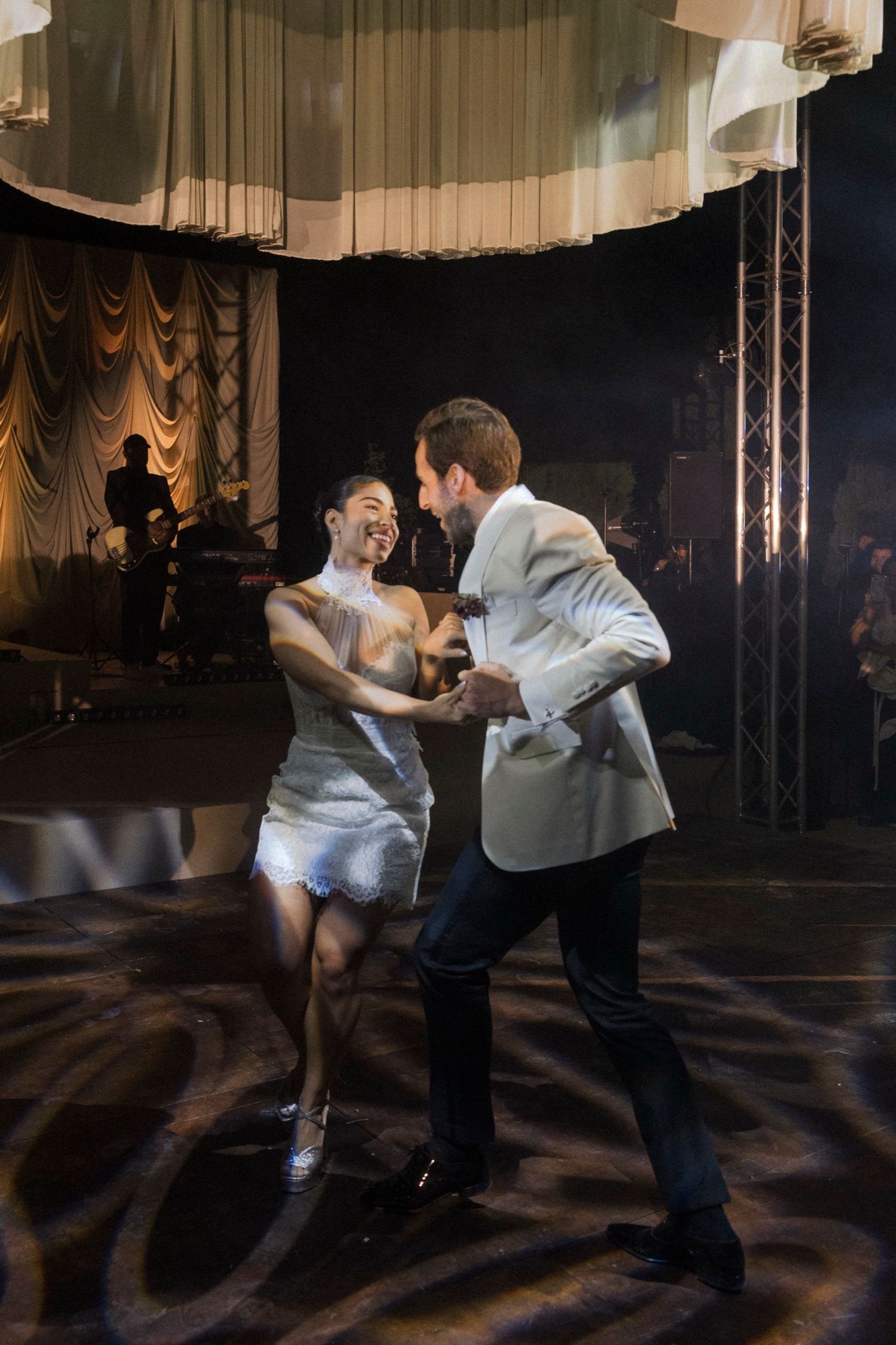 Dancers perform an energetic swing dance routine on stage with dramatic lighting and curtains in the background.
