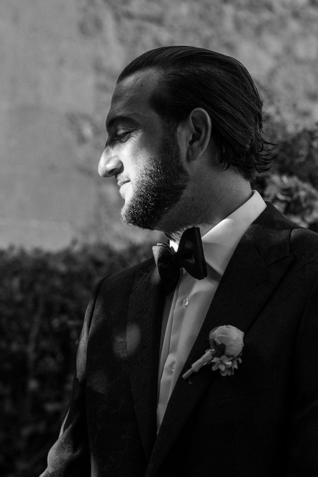 Black and white profile portrait of groom in tuxedo with boutonniere.